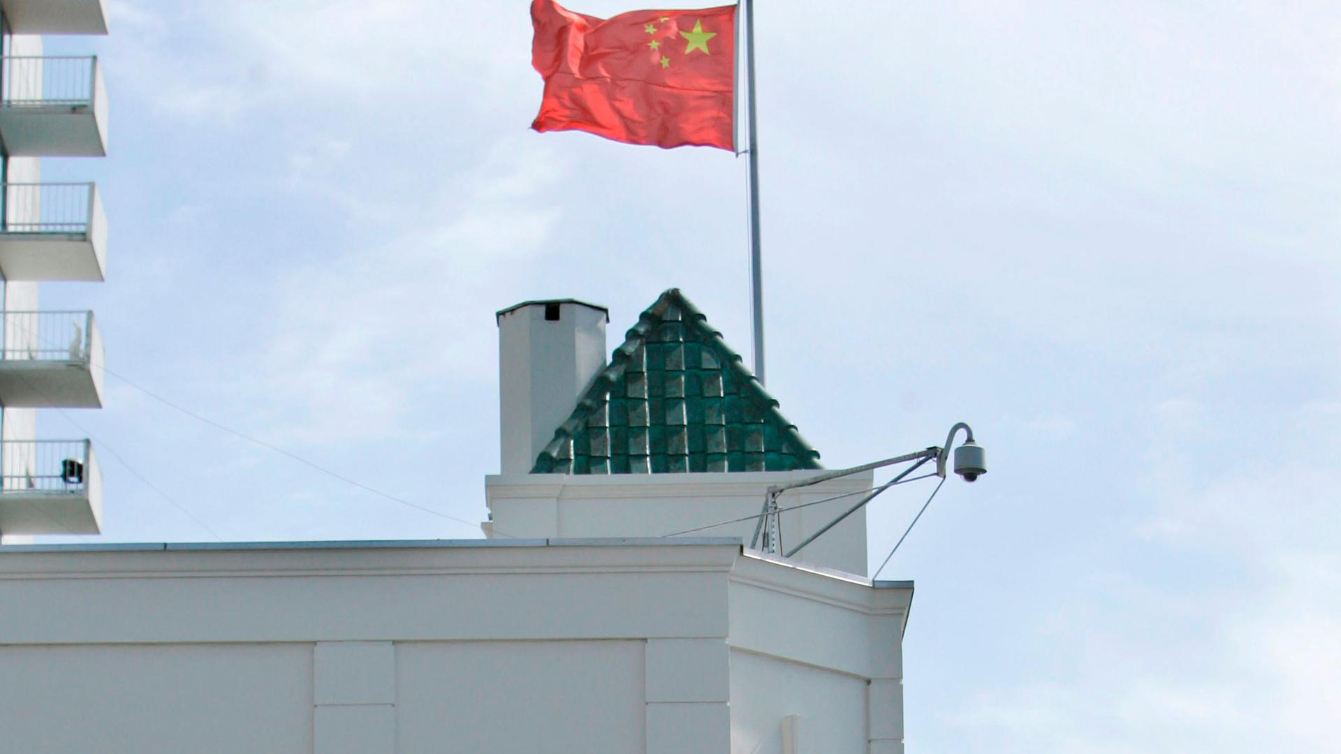 The top of a white building is shown with a Chinese flag flying.