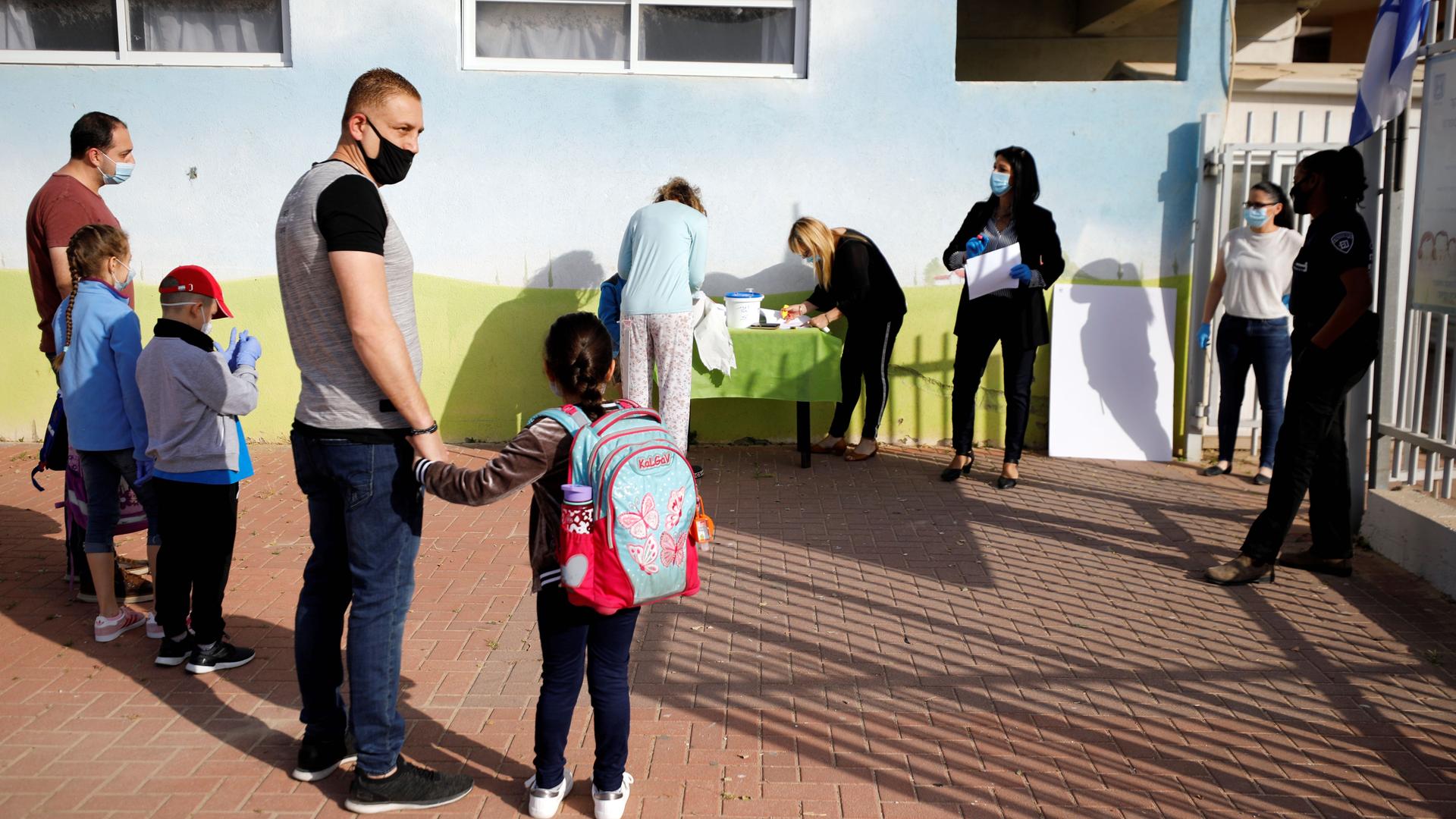 Parents wait with their children to enter their elementary school in Sderot as it reopens following the ease of restrictions preventing the spread of the coronavirus in Israel, May 3, 2020. 