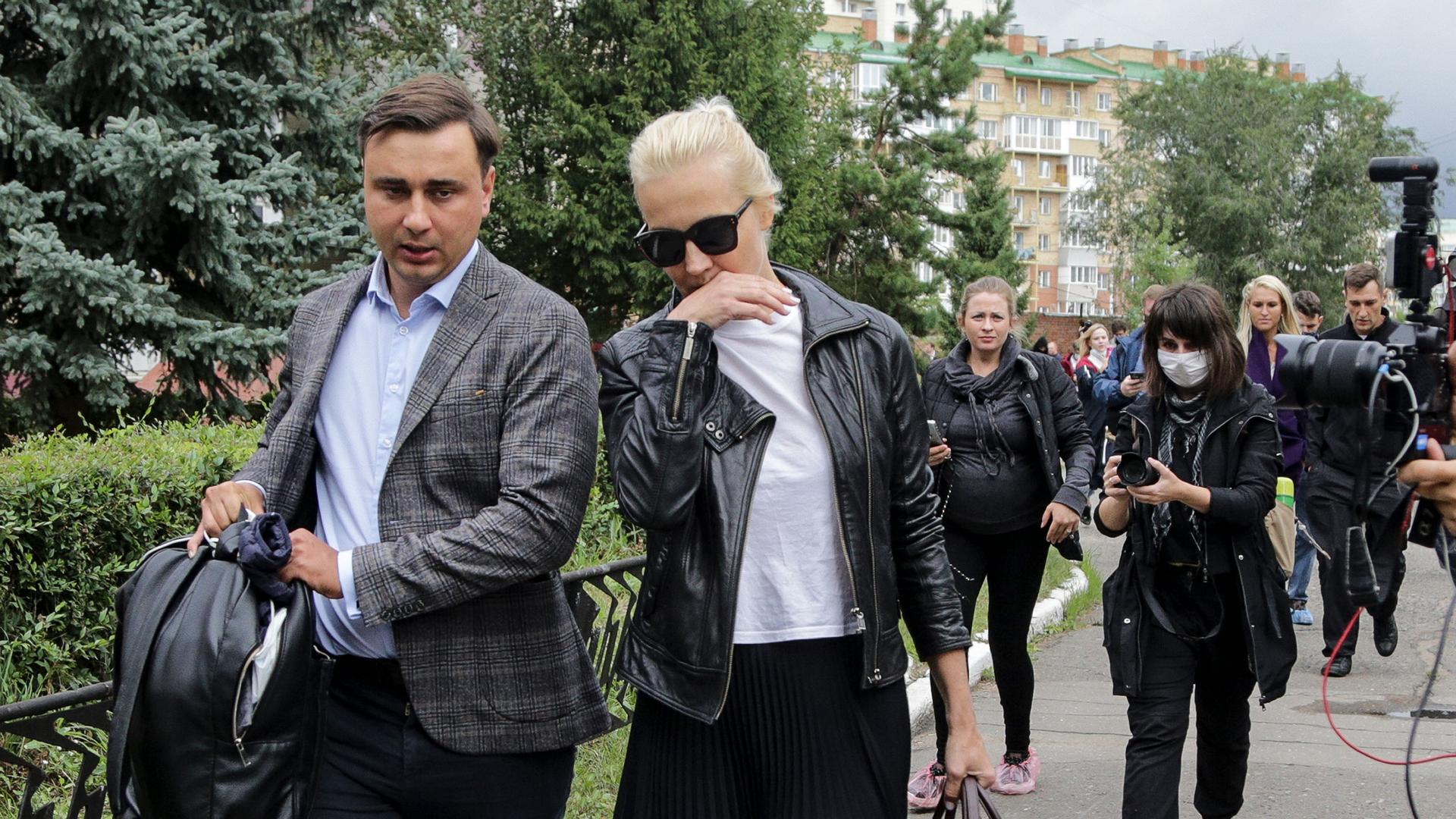 Alexei Navalny's wife Yulia, center, is shown walking and being followed by members of the media.