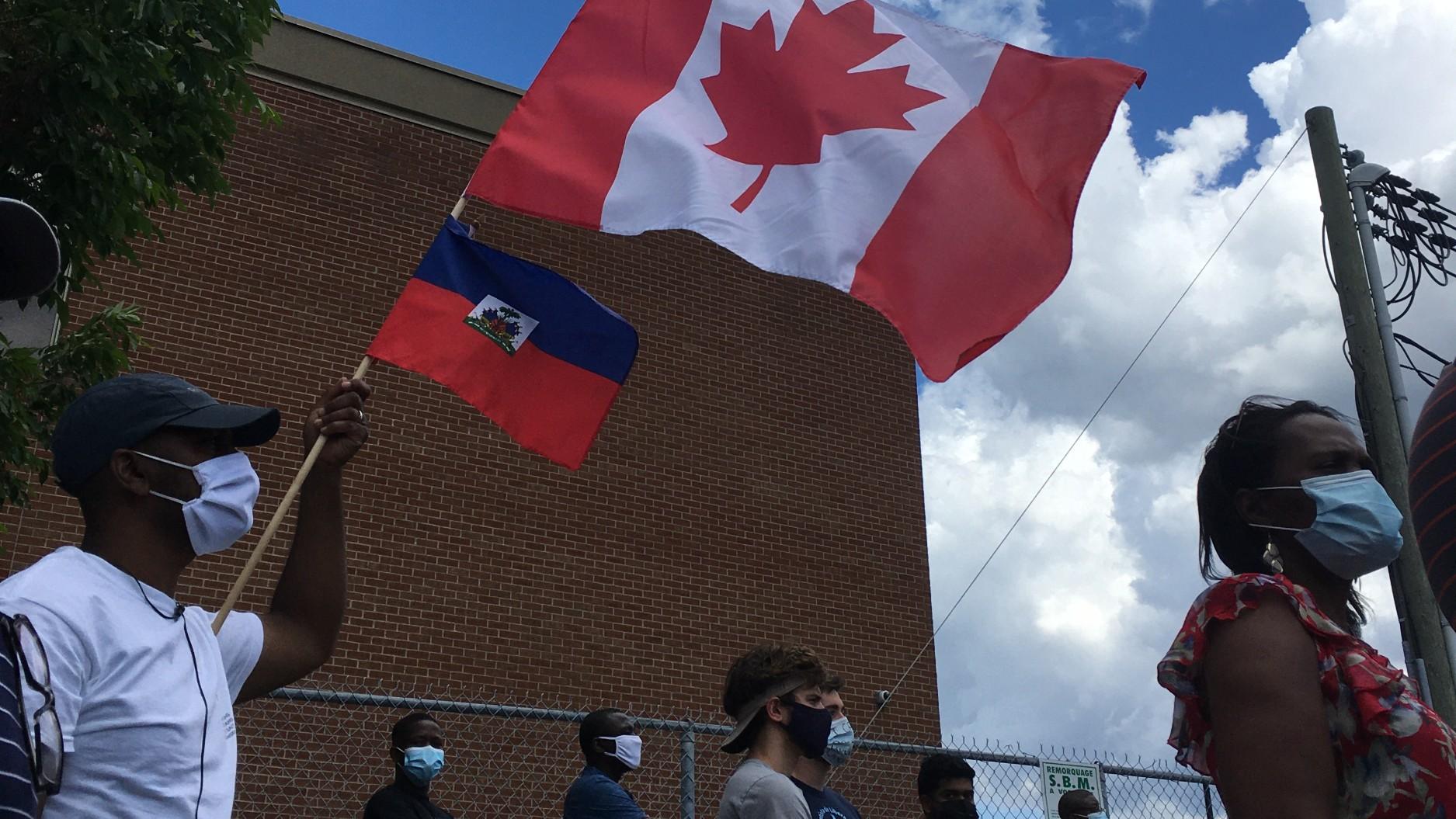 With Canadian and Haitian flags hoisted, marchers take part in demonstration in support of asylum-seekers working in Quebec's long-term care homes in Montreal, Canada, in June.
