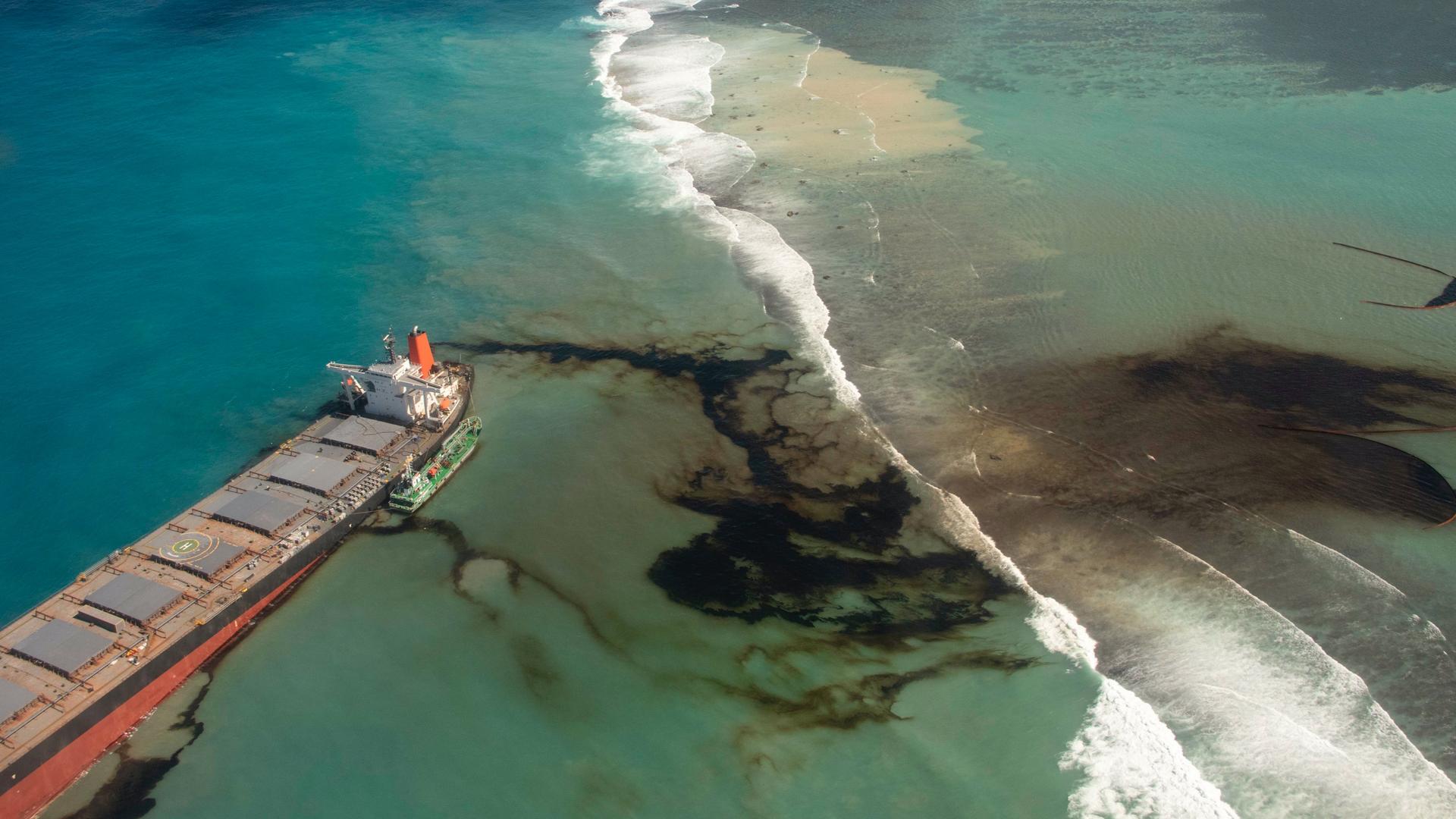 A long, narrow boat leaks black oil into the Indian Ocean off coast of Mauritius blue waters
