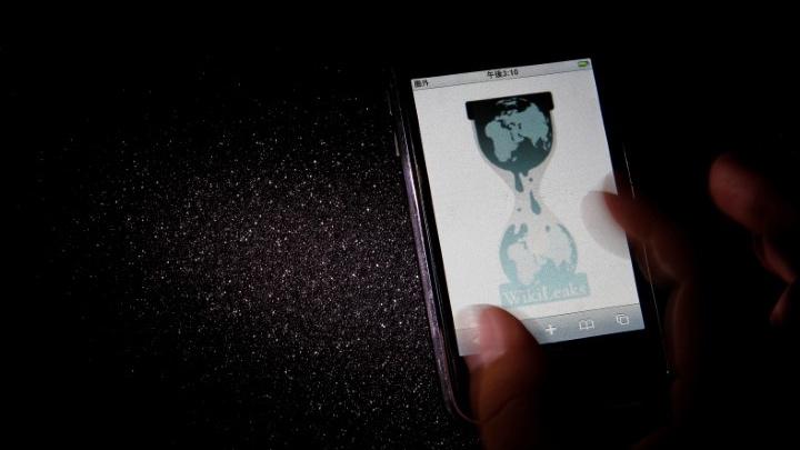 A hand holds a smartphone with Wikileaks webpage logo
