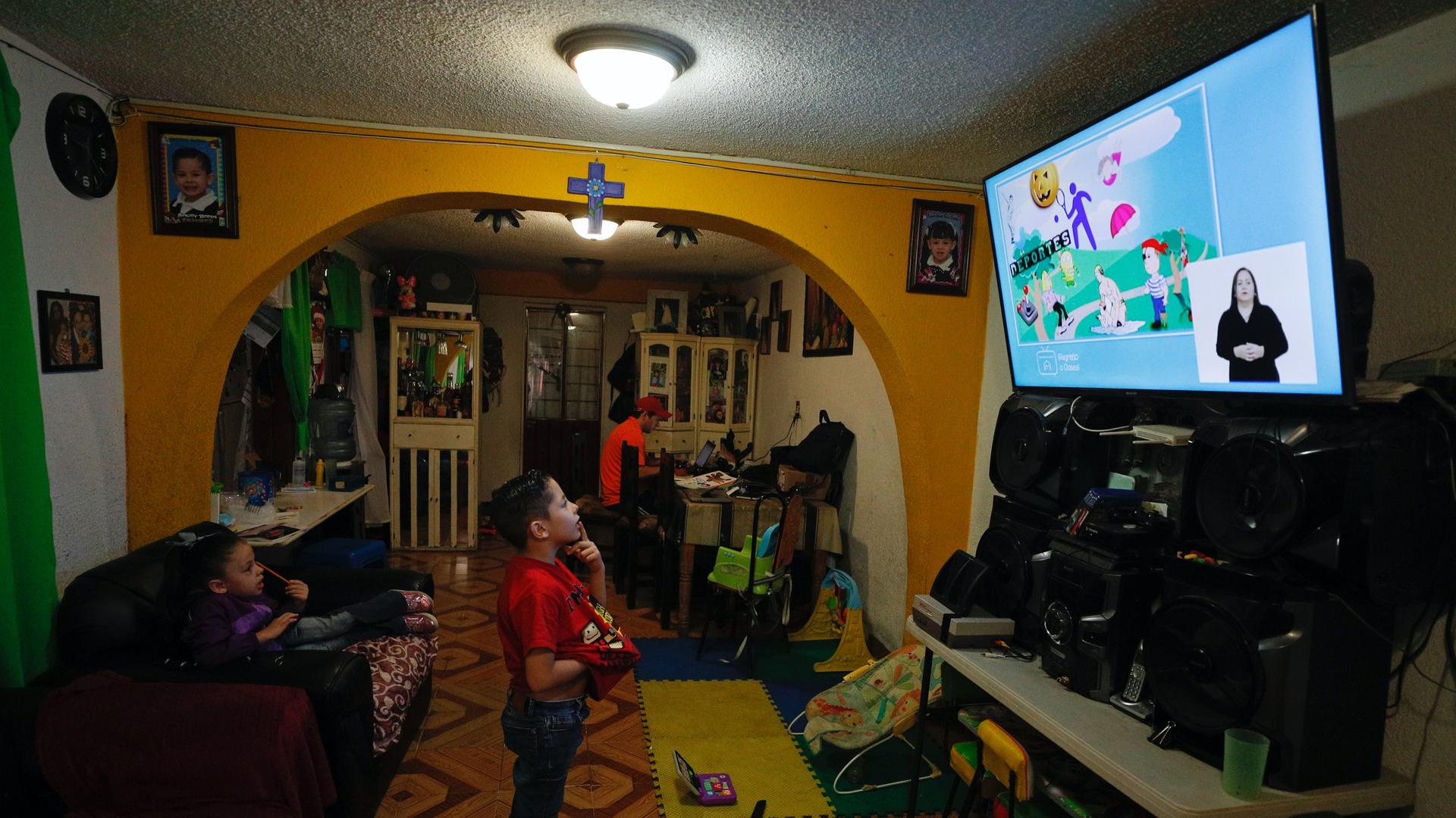 A child looks at a TV screen in a living room with orange painted walls. 