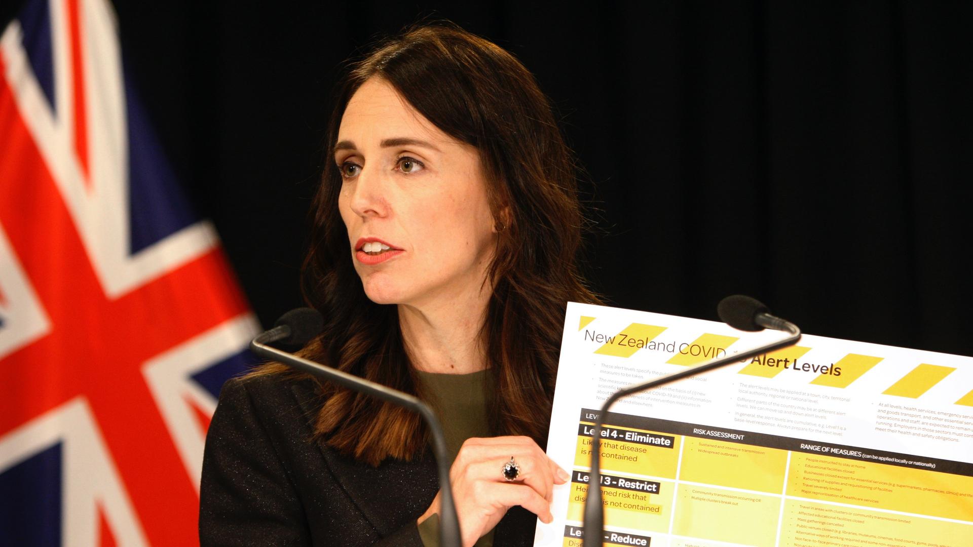 A woman leader holds up a COVID-19 chart card. 