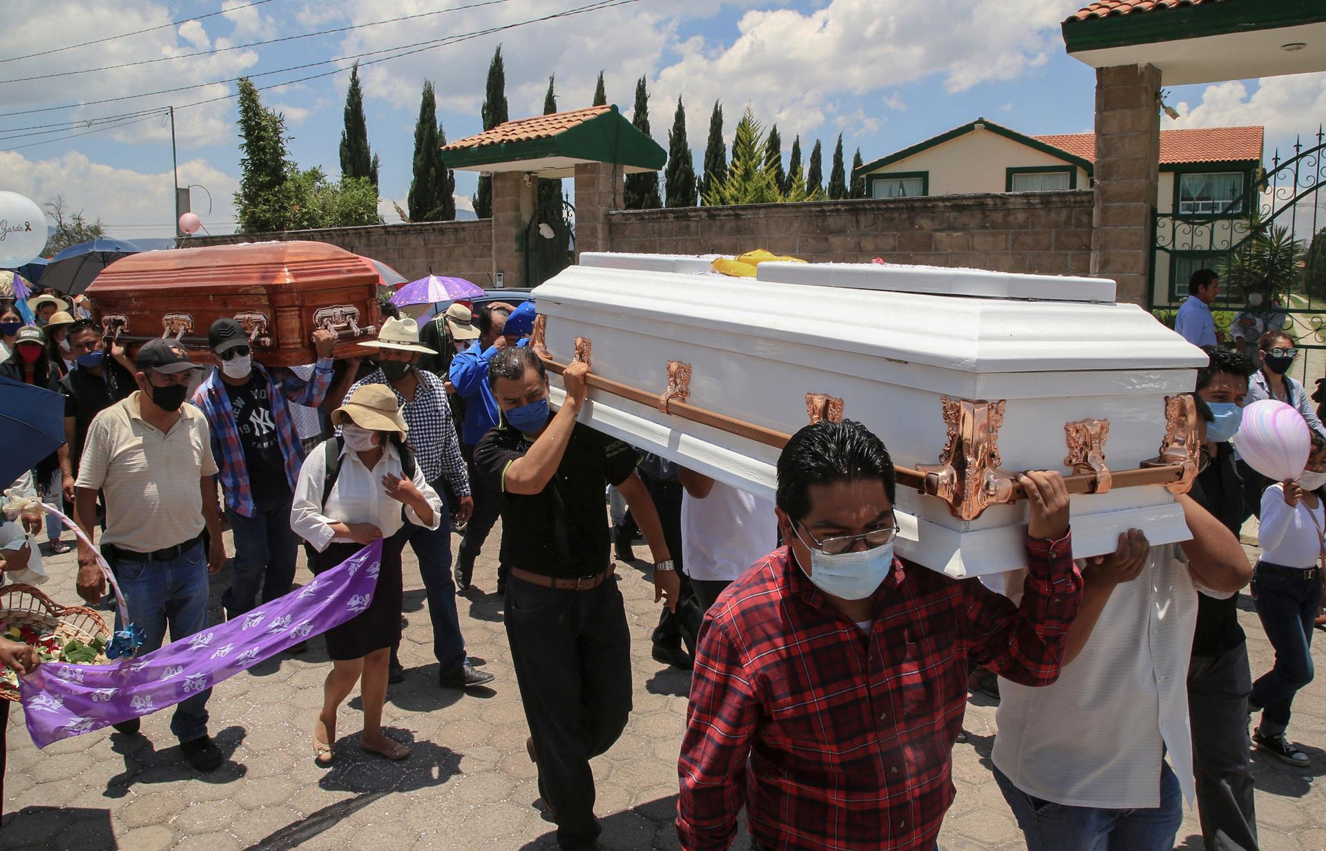 A crowd carries two caskets. 