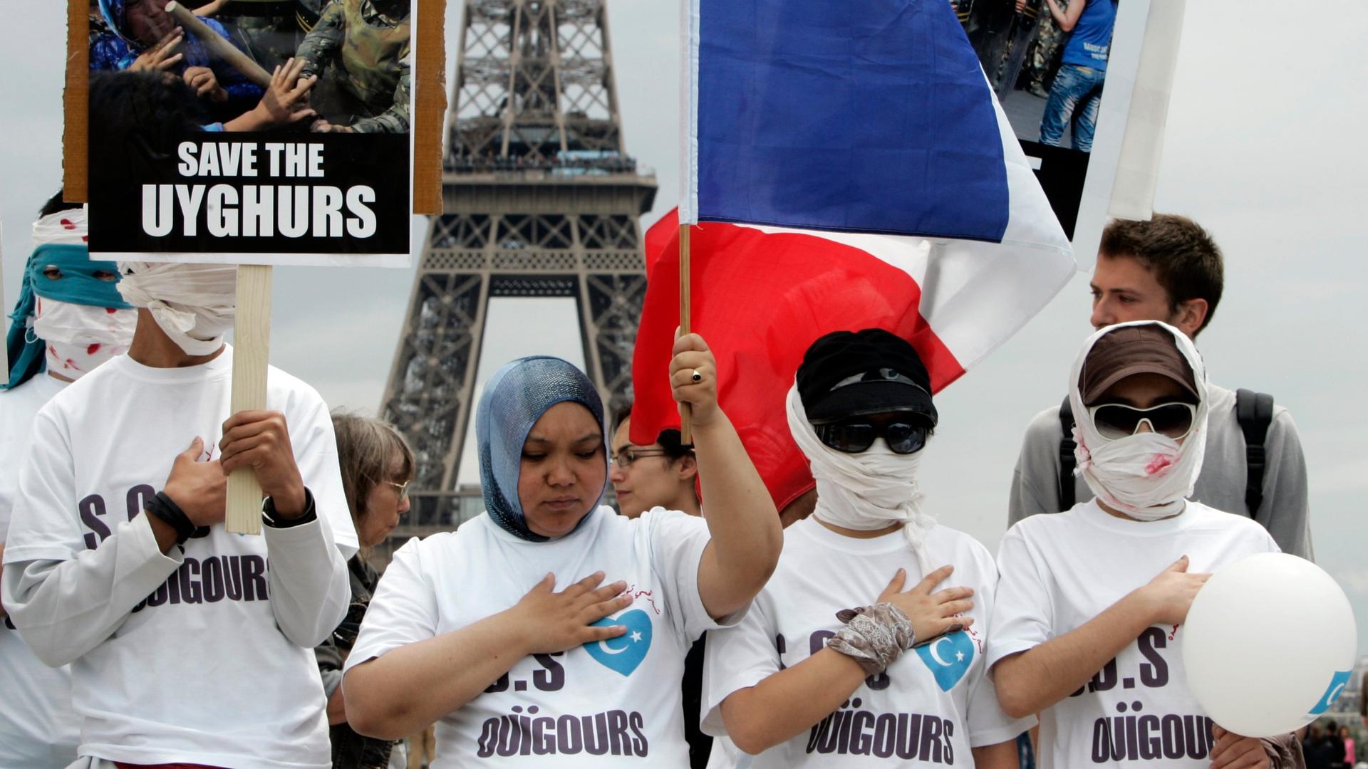 Uighur protesters, wearing bandages over mock wounds, hold placards and wave a French flag as they take part in a demonstration condemning violence in China's Xinjiang province, at the Trocadero near the Eiffel Tower in Paris, France, July 8, 2009.