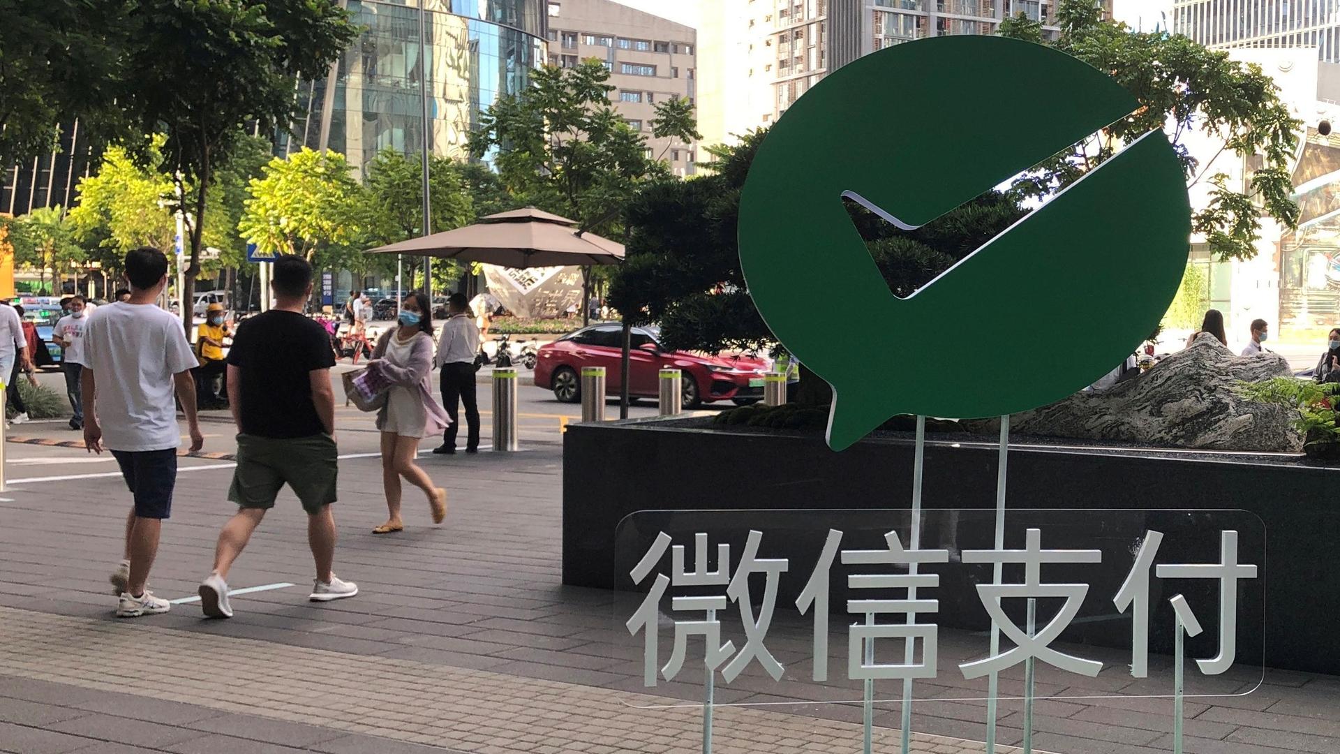People walk past a Wechat Pay sign at the Tencent company headquarters in Shenzhen, Guangdong province, China, Aug. 7, 2020.