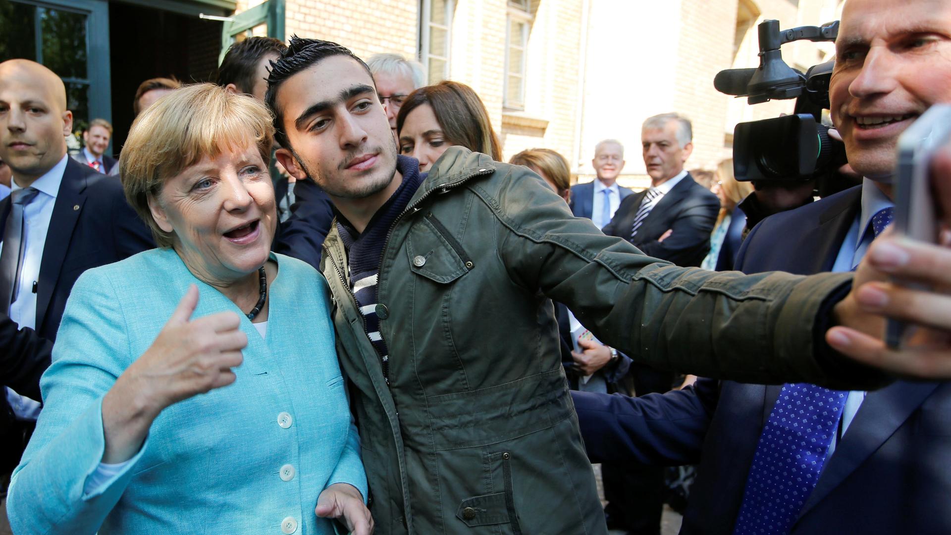 Syrian refugee Anas Modamani takes a selfie with German Chancellor Angela Merkel outside a refugee camp near the Federal Office for Migration and Refugees after registration at Berlin's Spandau district, Germany, on September 10, 2015. 