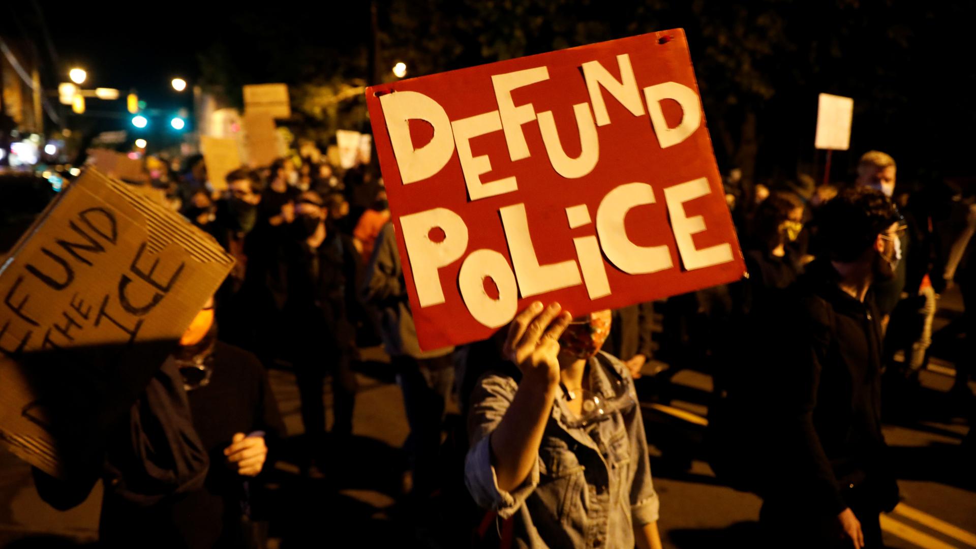 Demonstrators hold a sign reading "Defund the police" during a protest over the death of a Black man, Daniel Prude, after police put a spit hood over his head during an arrest on March 23, in Rochester, New York, September 6, 2020.