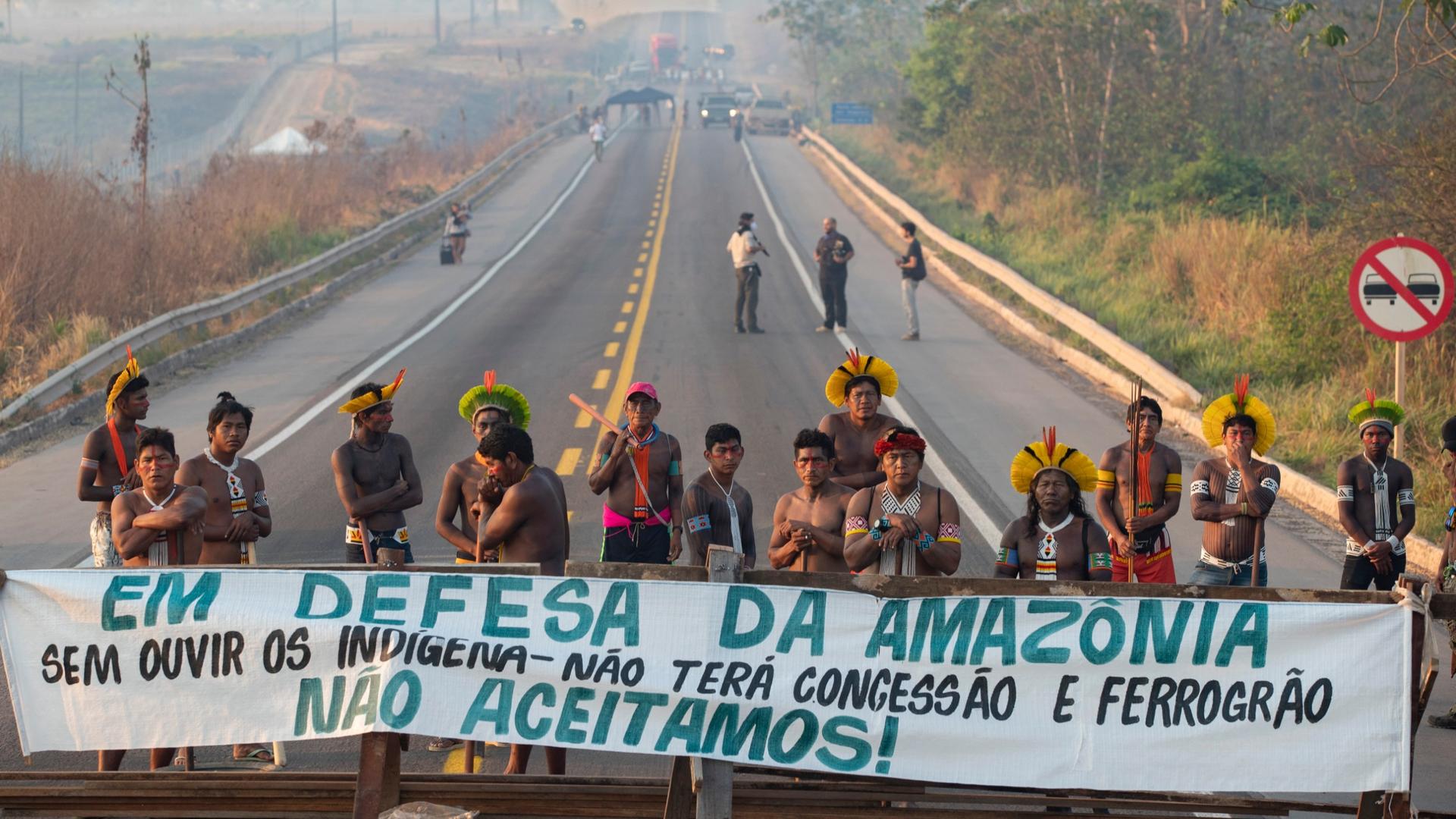 Kayapó Indigenous protesters block highway BR-163 with a banner that reads in Portuguese "Defending the Amazon. Without listening to Indigenous people, there will be no concession and nor grain railway," near Novo Progresso, Pará state, Brazil, Aug. 17, 2