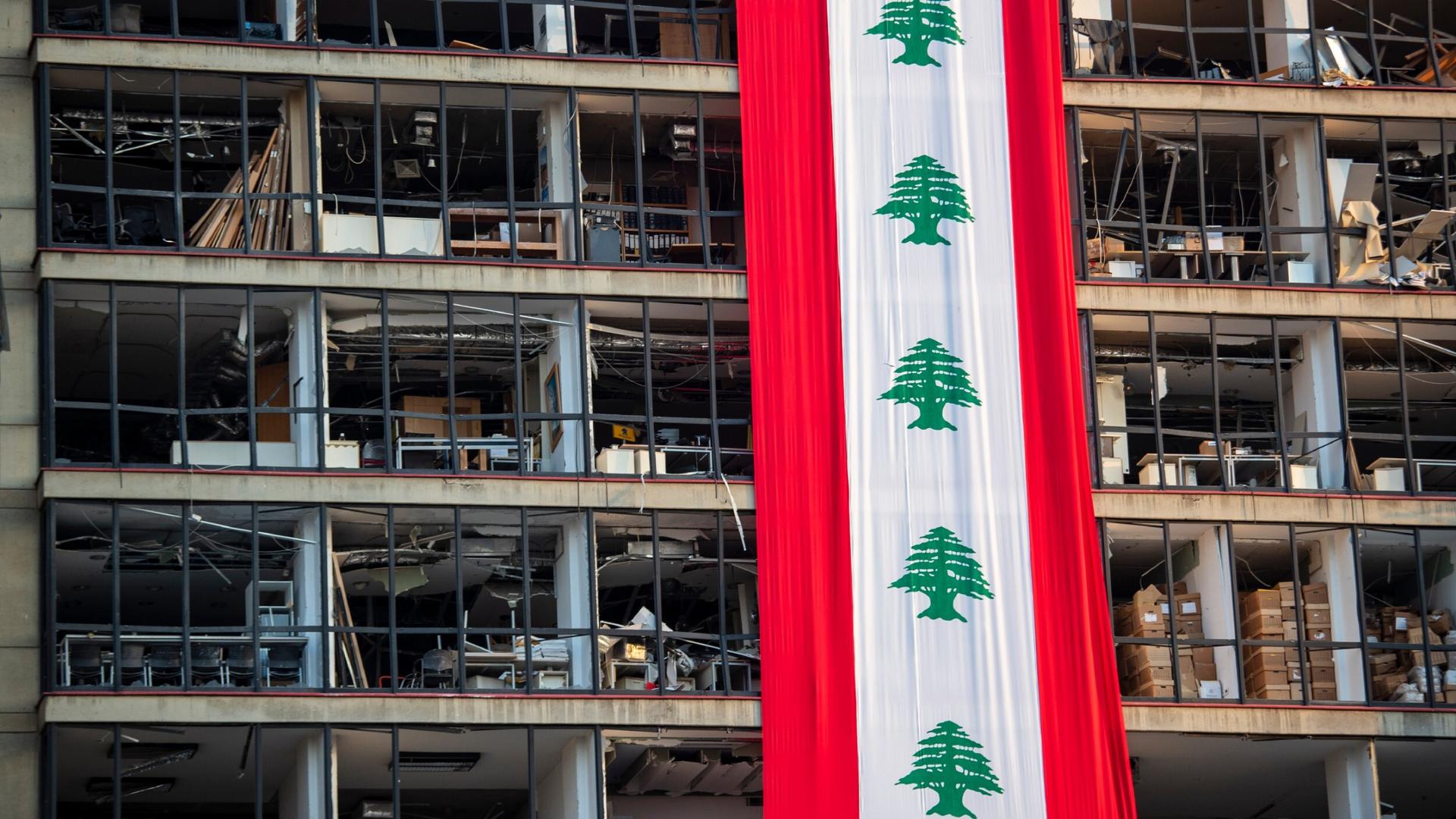 A banner with representations of the Lebanese flag hangs on a damaged building in a neighborhood near the site of the explosion