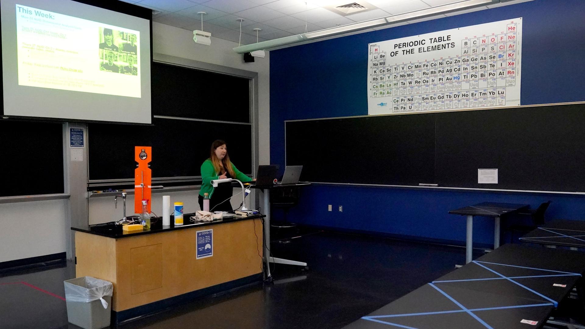 Sections of a table are seen blocked off with tape as assistant professor Jennifer Guerard speaks into laptops while teaching a foundations of chemistry remote class at the US Naval Academy, Aug. 24, 2020, in Annapolis, Md.
