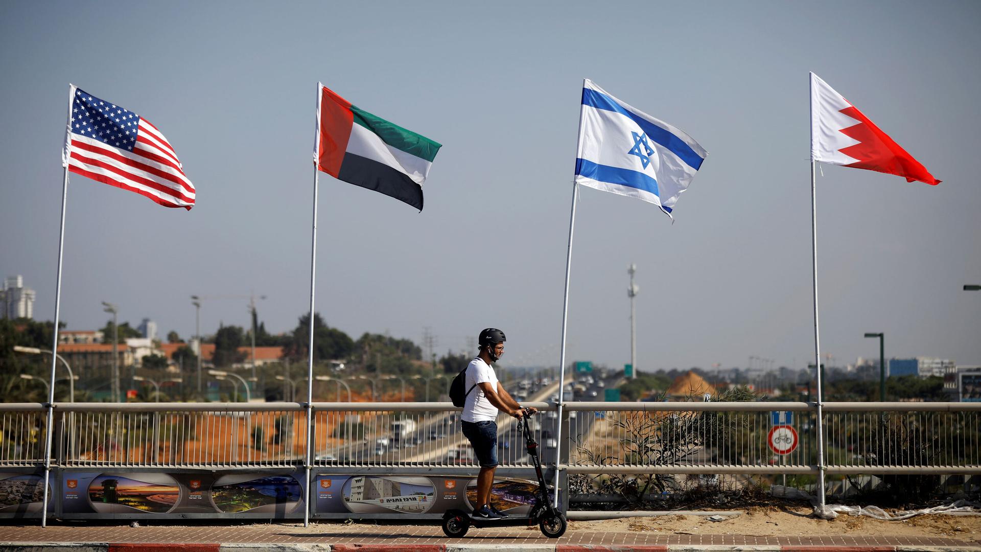 A man rides a scooter past the flags of the US, United Arab Emirates, Israel and Bahrain along a road in Netanya, Israel, Sept. 14, 2020.