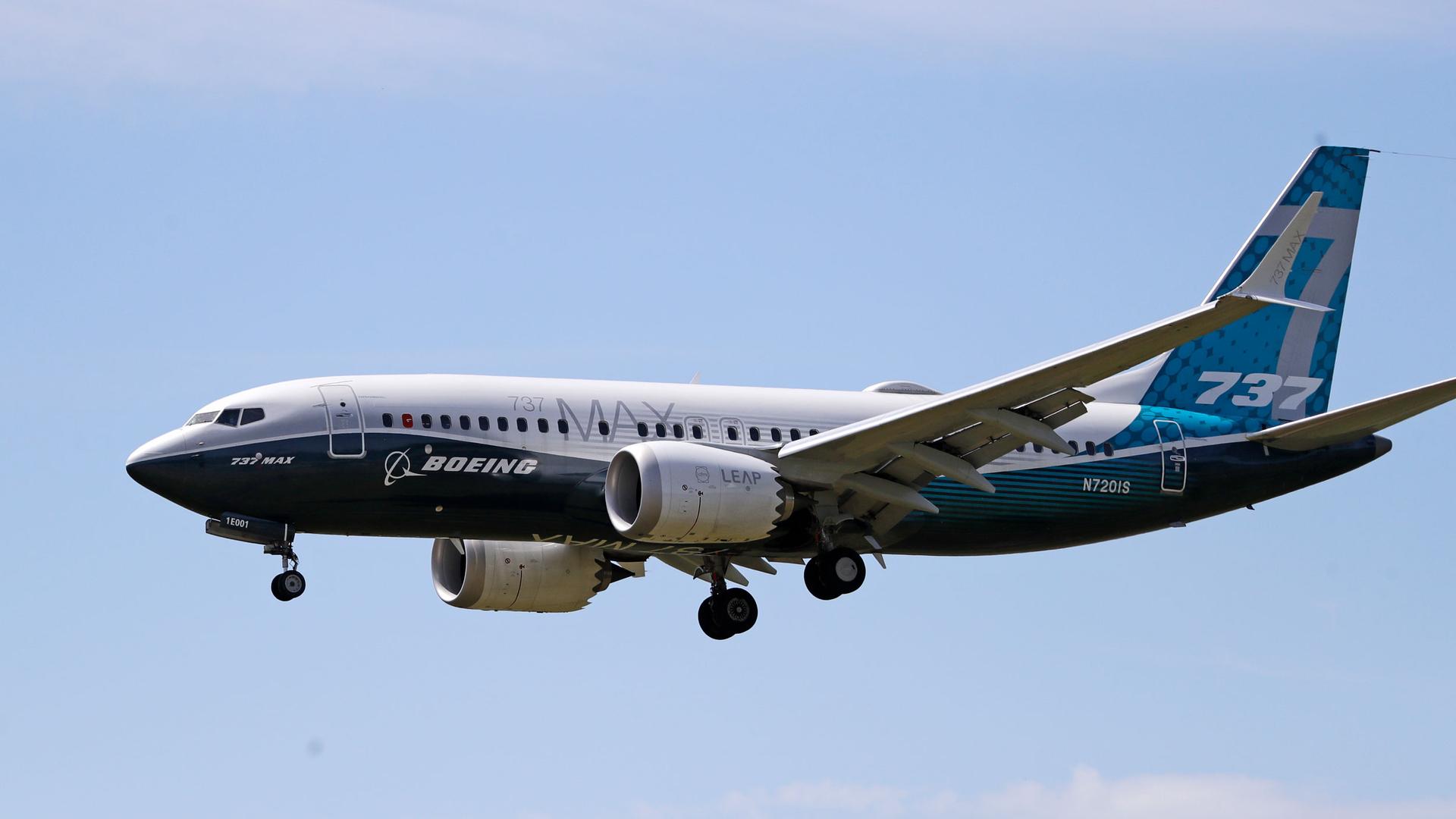 A Boeing 737 Max jet is shown in the air with its wheels down prepared for a landing.
