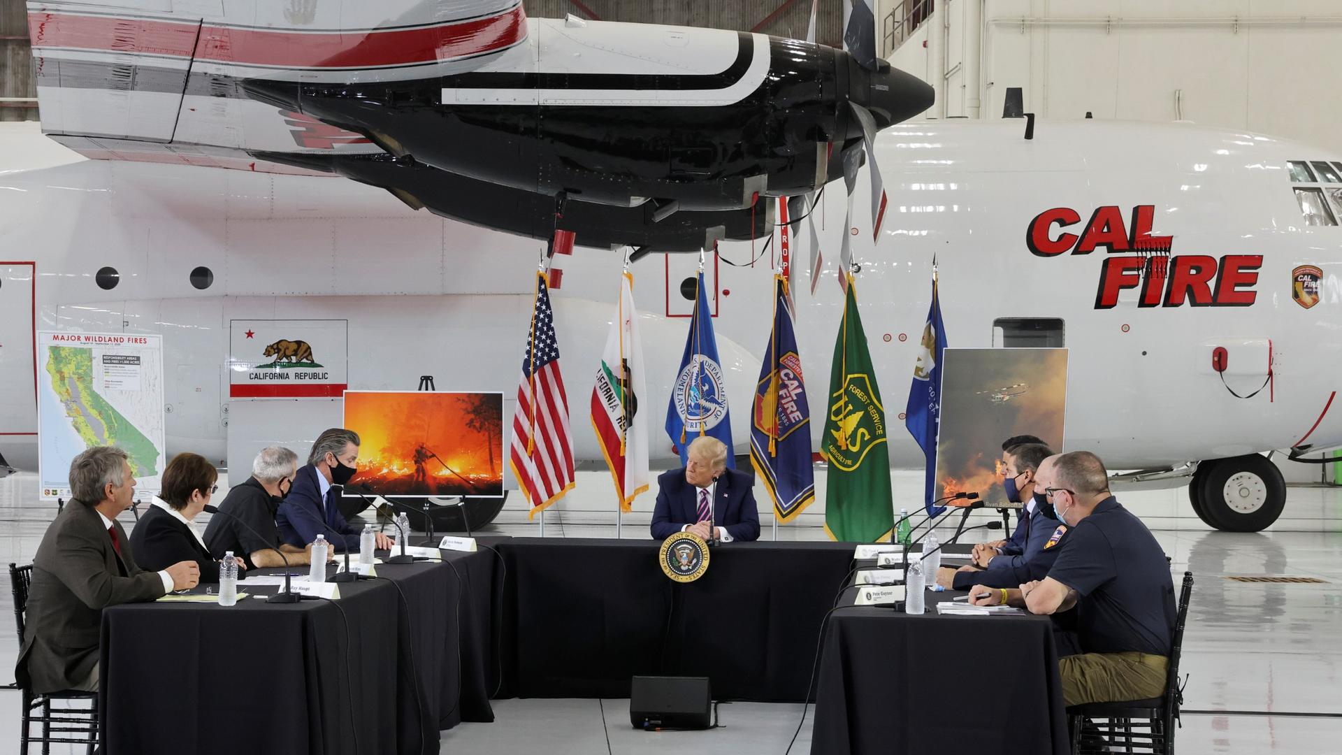 US President Donald Trump sits in front of a CAL FIRE firefighting aircraft as California Governor Gavin Newsom speaks during a briefing on wildfires in McClellan Park, Calif., Sept. 14, 2020. 