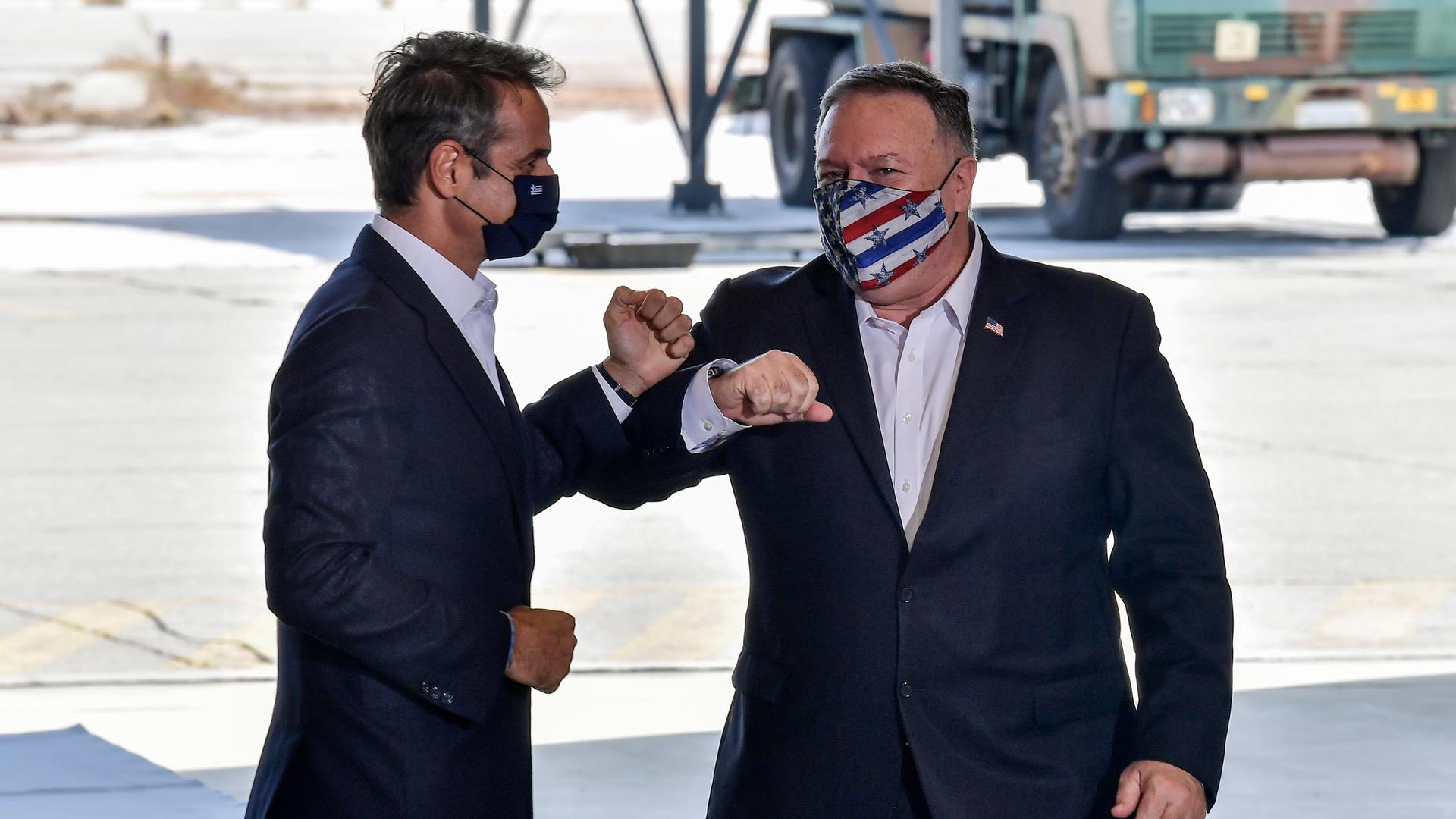 US Secretary of State Mike Pompeo, right, and Greek Prime Minister Kyriakos Mitsotakis are shown both wearing dark blazers and bumping elbows.
