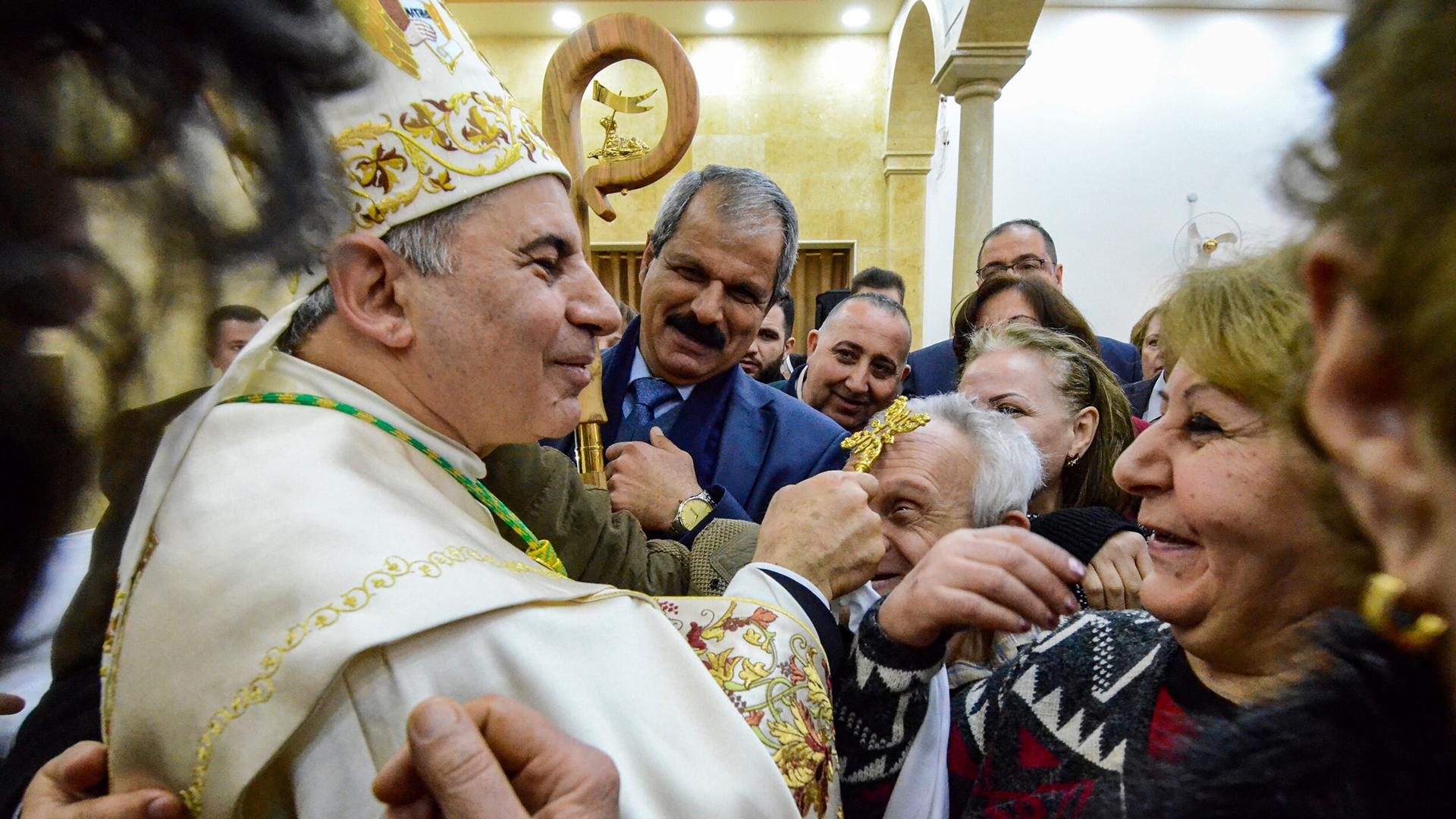 An archbishop blesses a man with his golden cross 