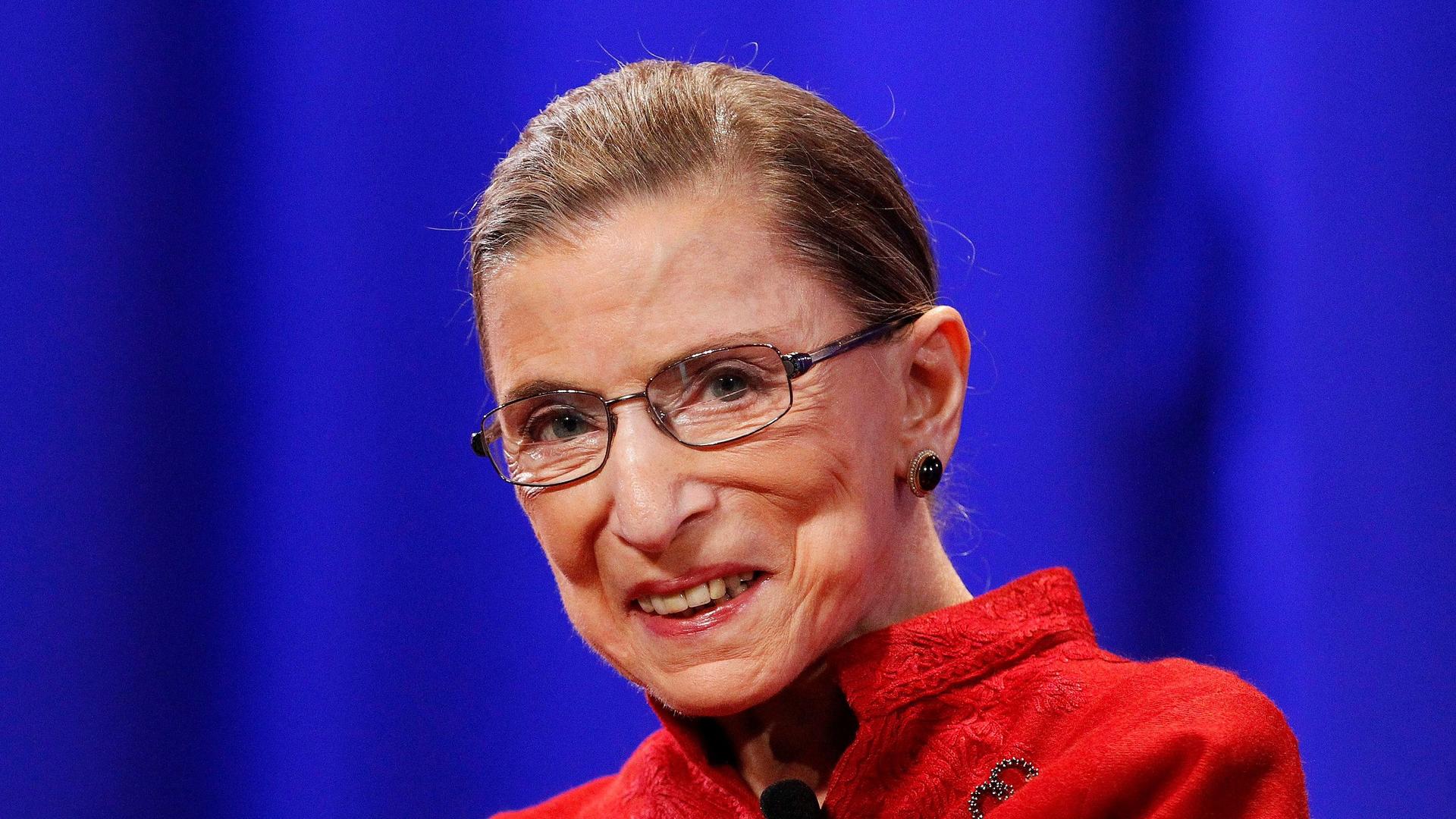 the late Supreme Court Justice Ruth Bader Ginsburg wears a bright red suit jacket