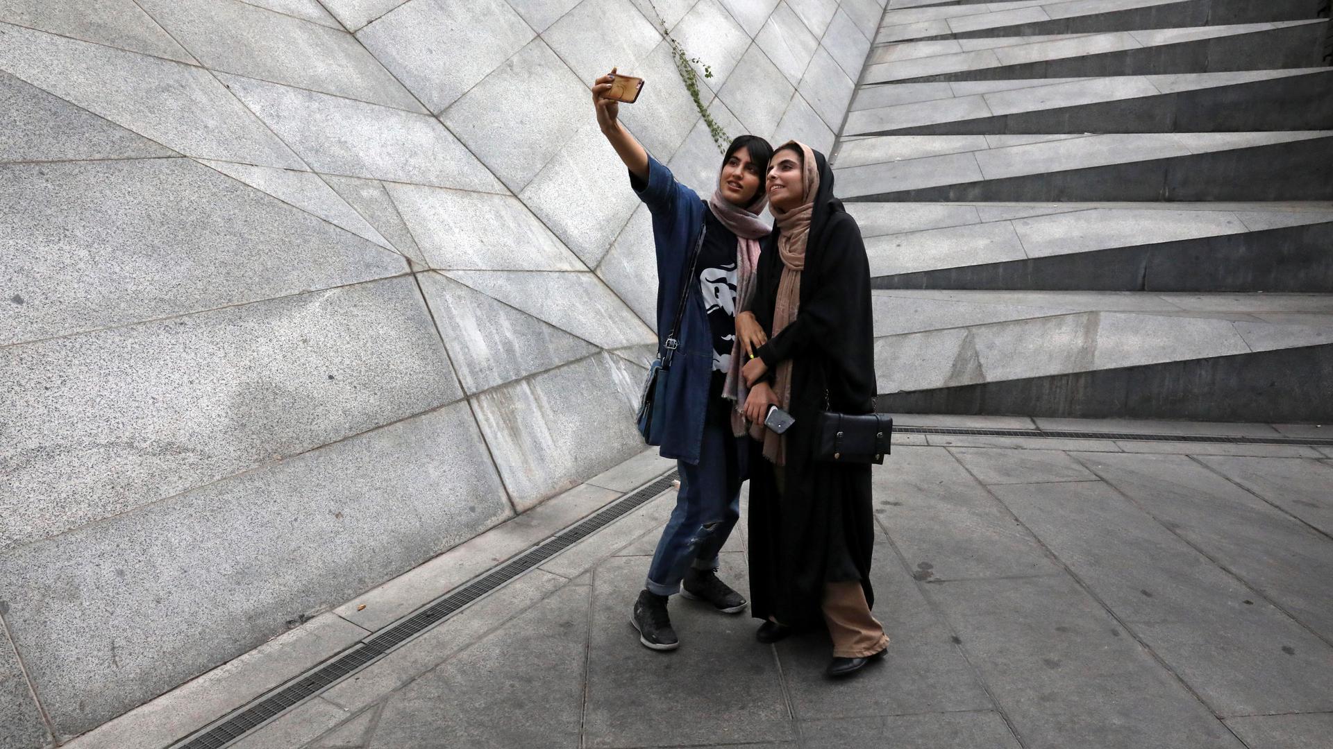 Two Iranian women take a selfie outside a shopping mall in northern Tehran, Iran, on July 2, 2019.