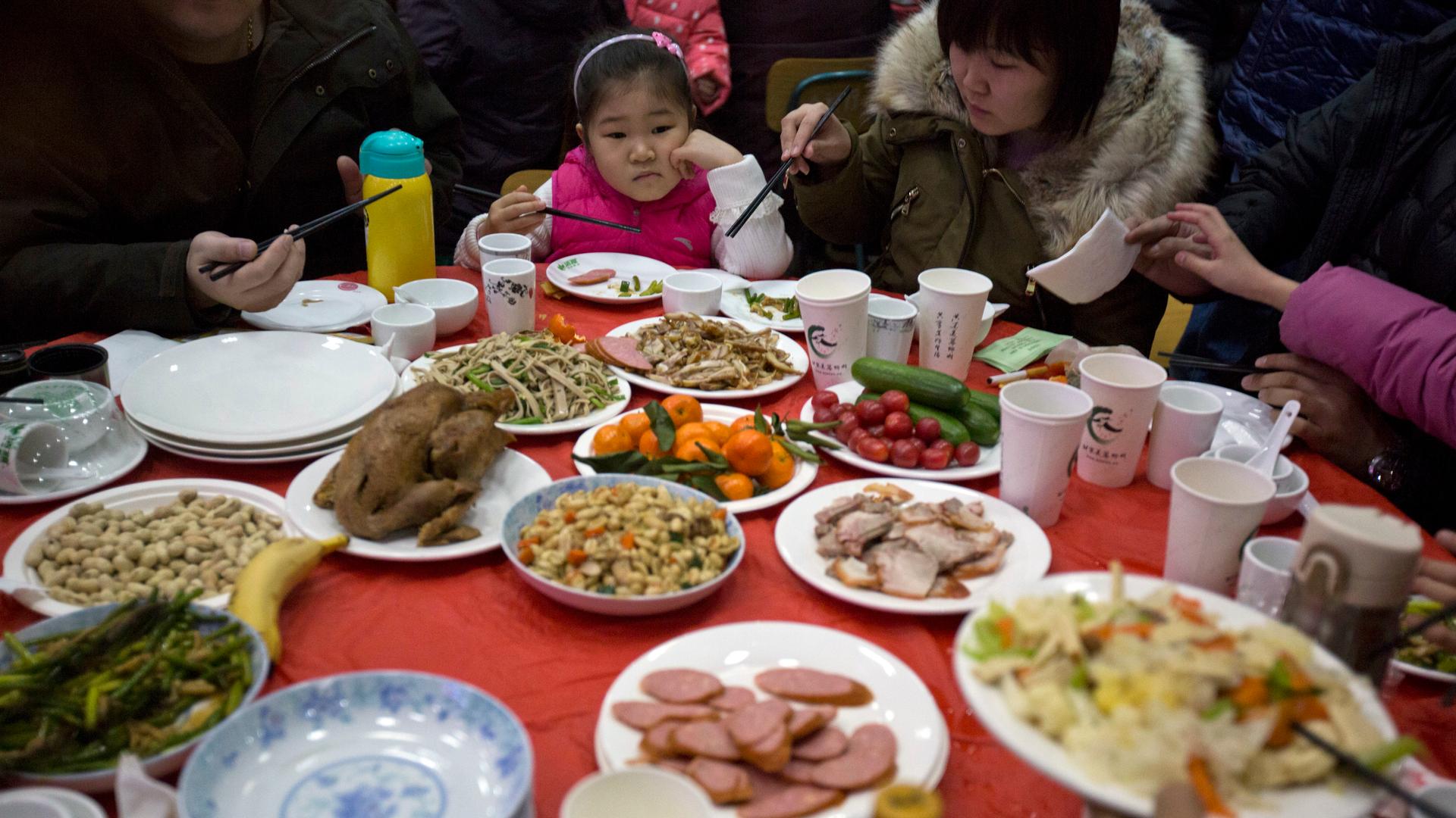 A Chinese girl looks upon a table full of food during a "1,000 people dumpling feast" in Liuminying village on the outskirt of Beijing, China, Jan. 27, 2017.