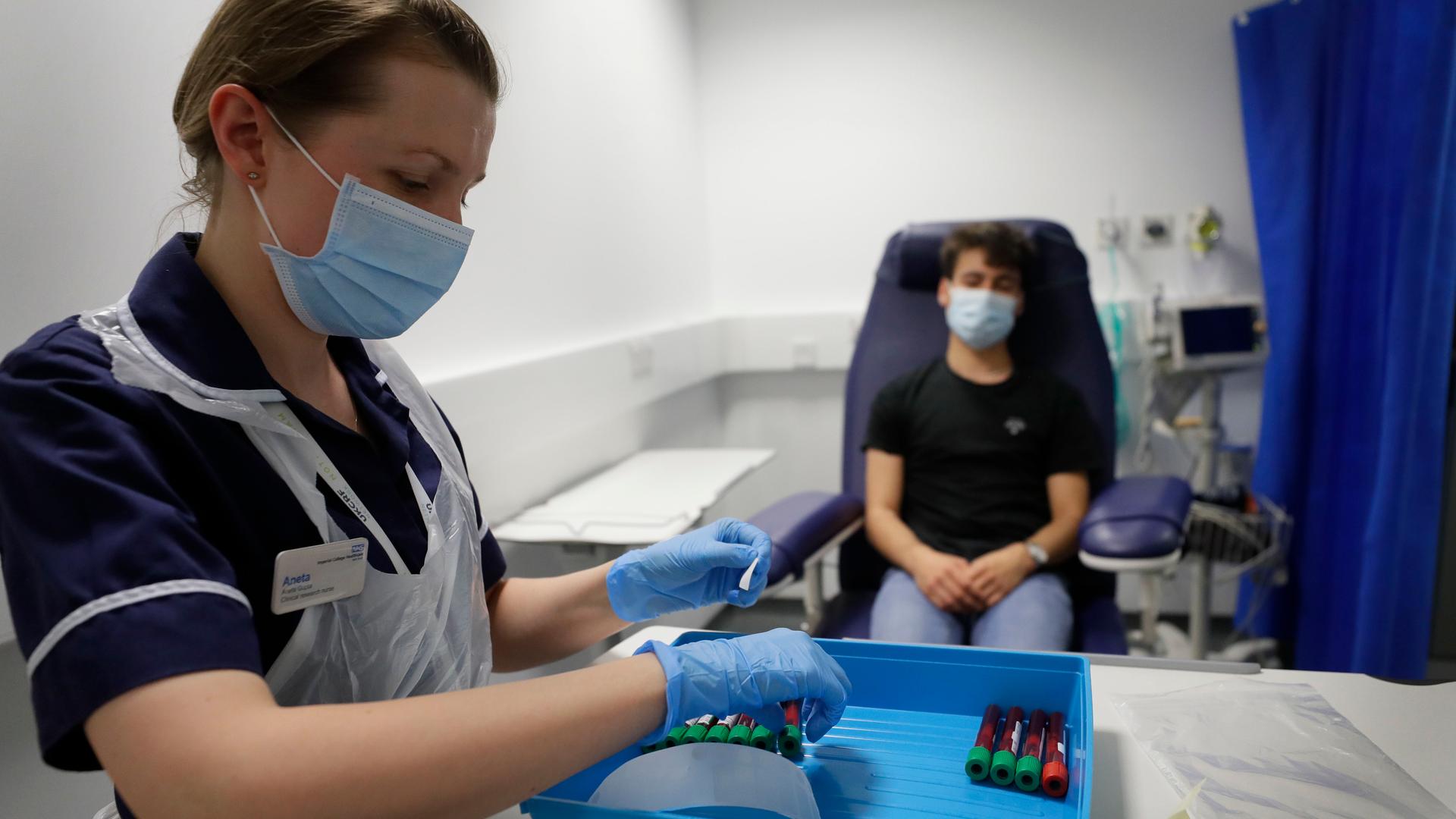 Clinical Research Nurse Aneta Gupta labels blood samples from volunteer Yash during the Imperial College vaccine trial, at a clinic in London, Aug. 5, 2020. 