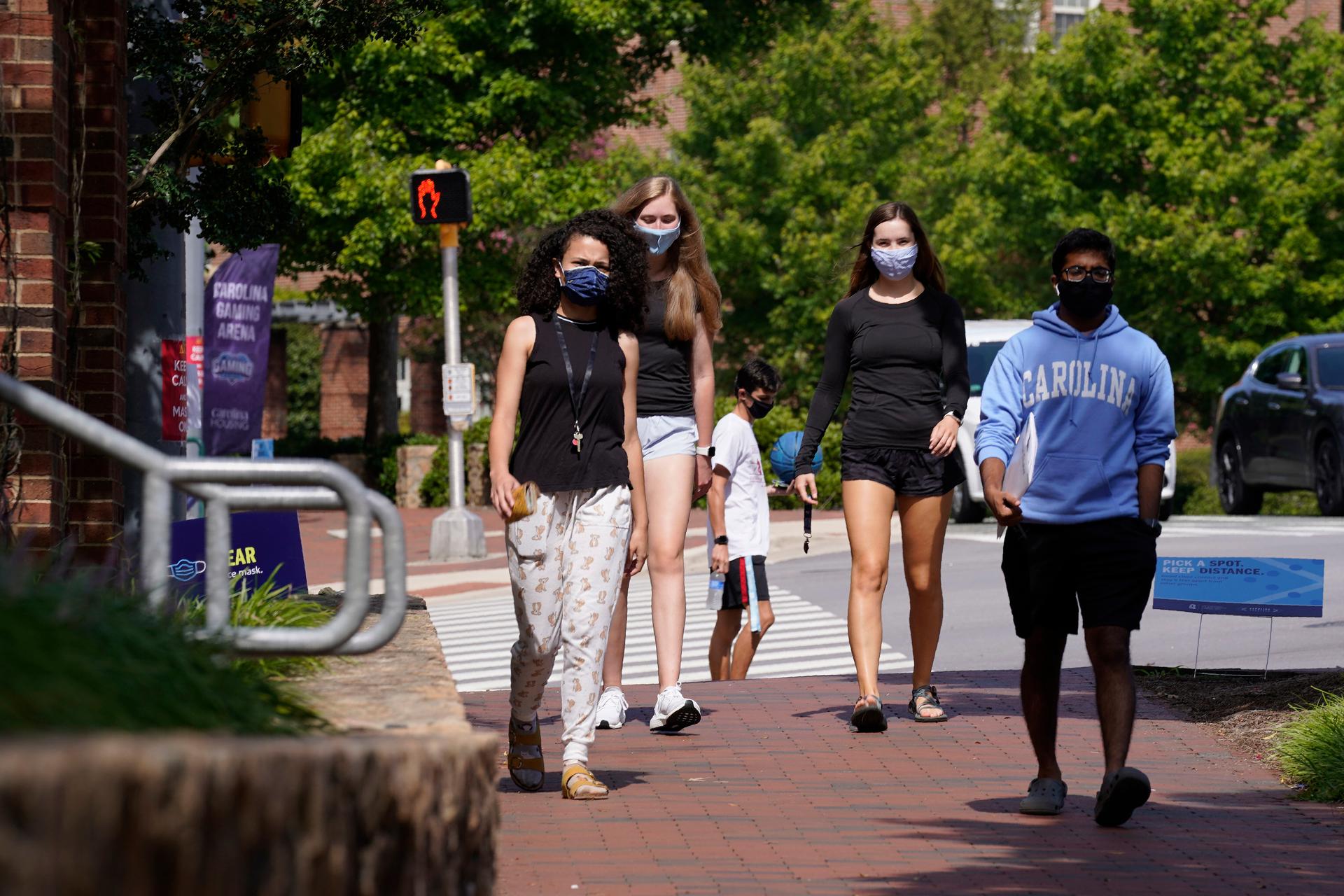 College students walking, wearing masks.