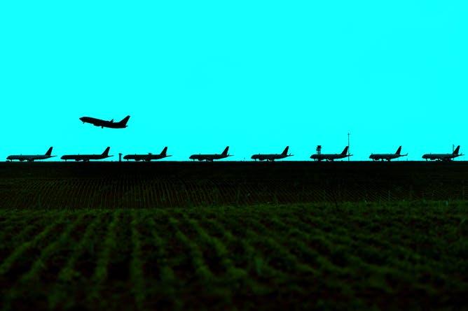 A silhouette of passenger jets lined up on a runway. 