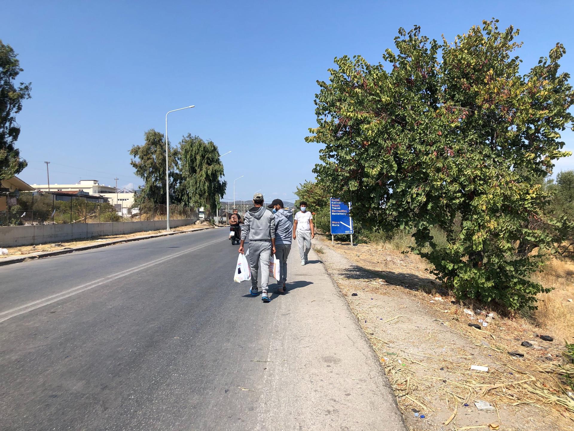 Two Syrian asylum-seekers return from a shopping trip to the port city of Mytilene, where they picked up rice, tomato sauce and other food. They say the food being distributed at the camp is not enough.