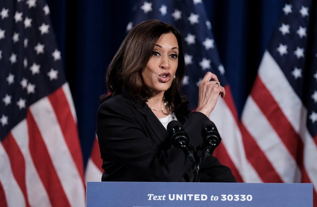 Kamala Harris standing in front of American flags