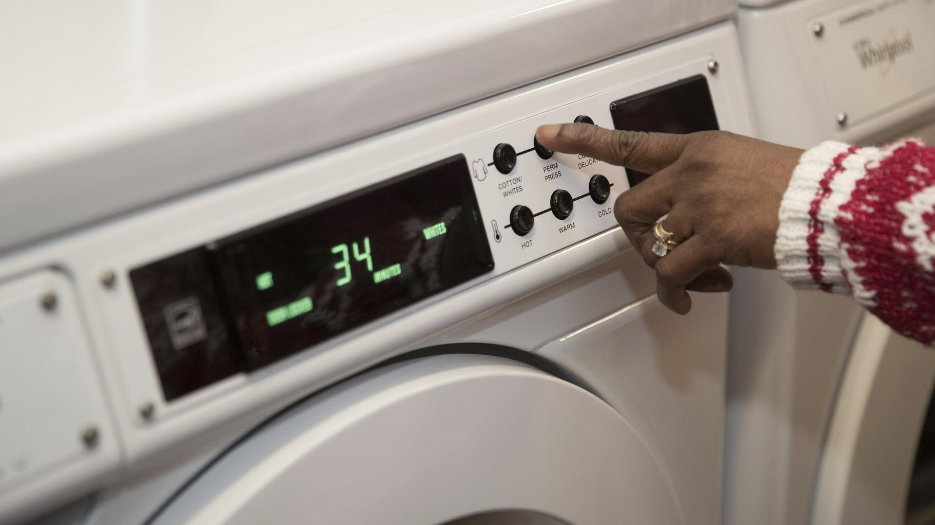 Hand reaching forward to set the timer on a washing machine