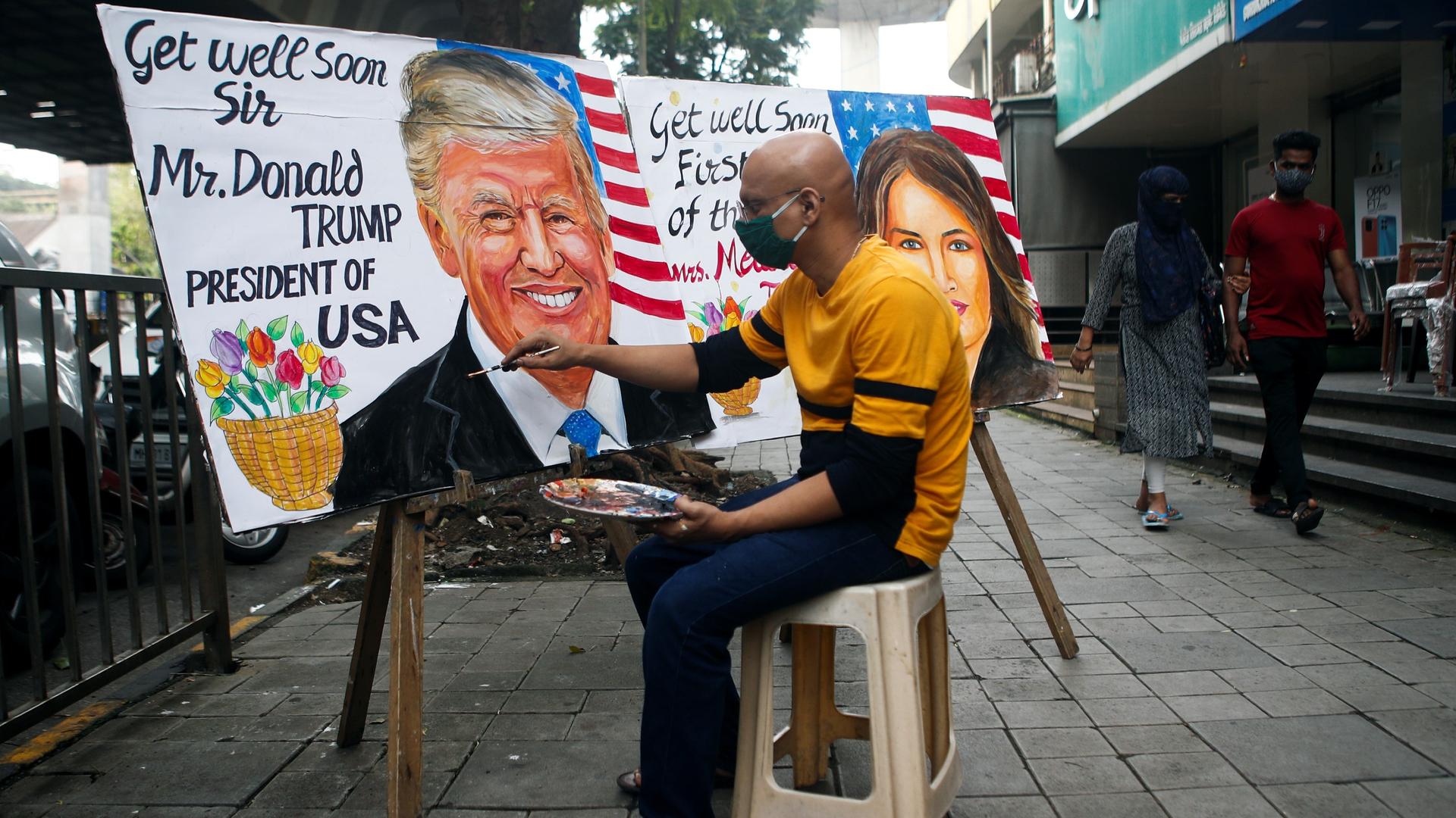A man paints a mural of US President Donald Trump and First Lady Melania Trump after they tested positive for the coronavirus disease (COVID-19), on a street in Mumbai, India, Oct. 2, 2020.