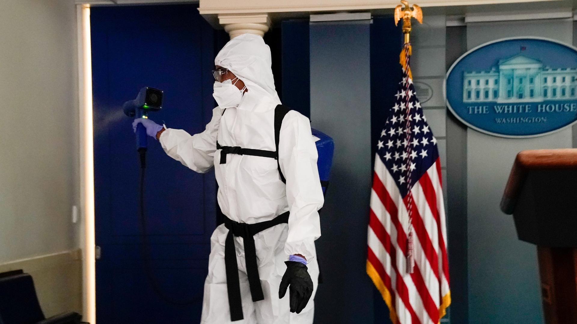 With full-body PPE and disinfecting equipment, a member of the White House cleaning staff sprays the press briefing room the evening of US President Donald Trump's return from Walter Reed Medical Center, in Washington, DC, Oct. 5, 2020.