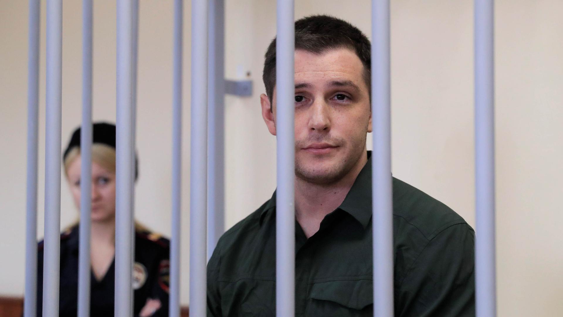 US ex-Marine Trevor Reed, who was detained in 2019 and accused of assaulting police officers, stands inside a defendants' cage during a court hearing in Moscow, Russia, March 11, 2020.