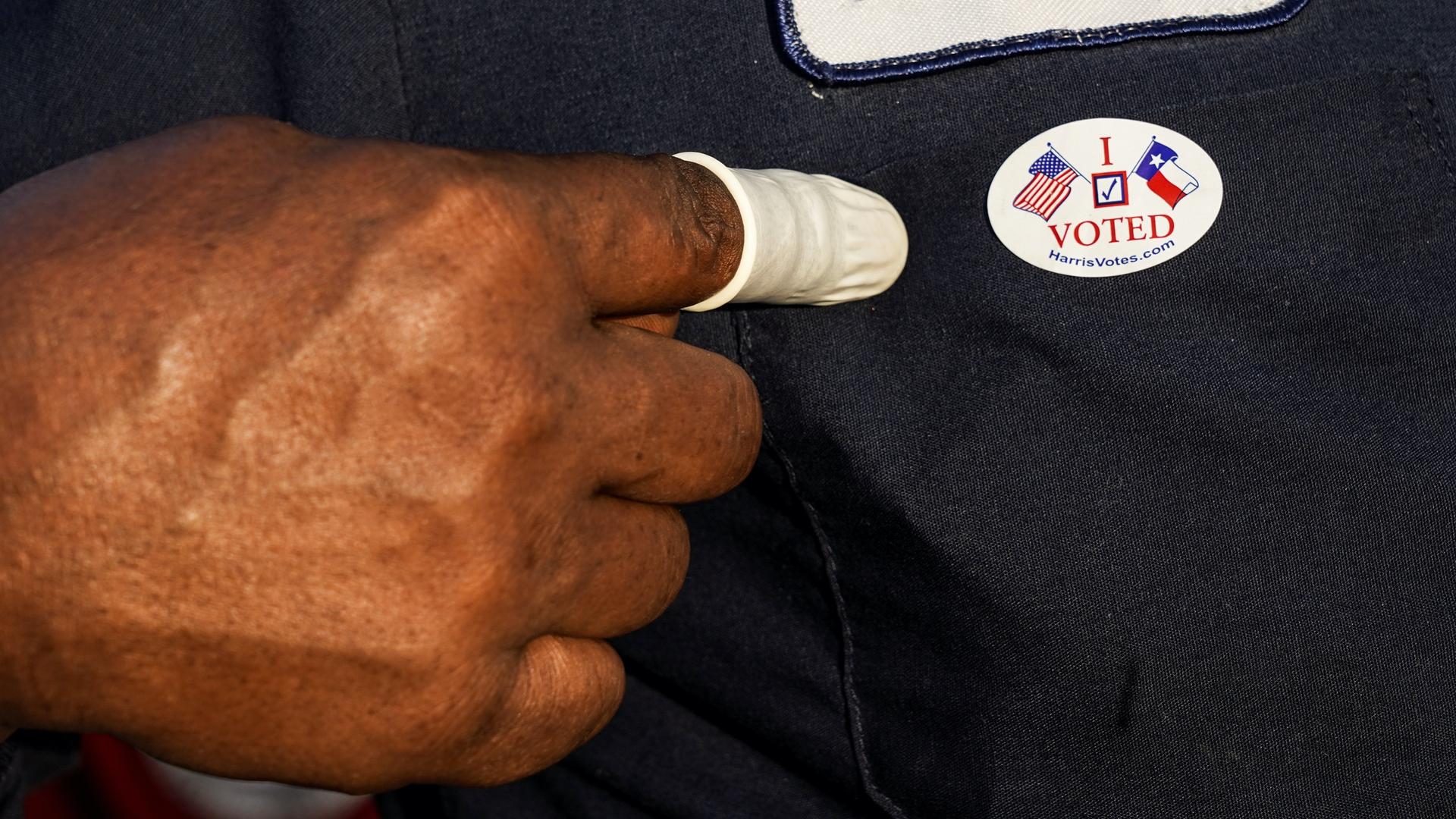 A person wearing a finger sack points at an "I Voted" sticker after casting ballot for the upcoming presidential election as early voting begins in Houston, Texas, Oct. 13, 2020. 
