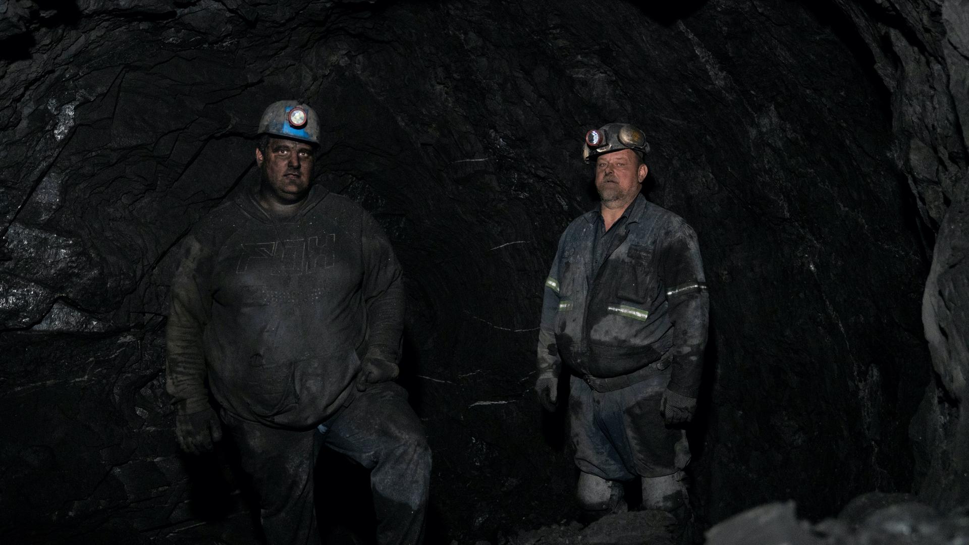 Two coal miners in uniform with skinned blackened from coal mining. 