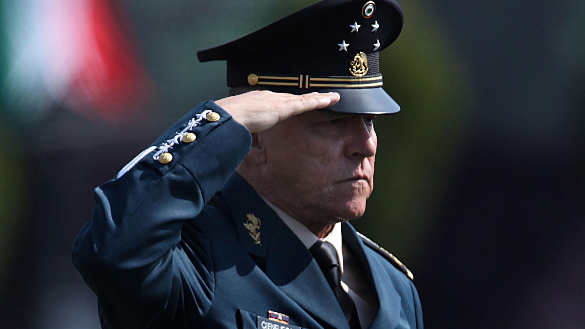 Mexico's Defense Secretary Gen. Salvador Cienfuegos Zepeda is shown wearing his military uniform and billed hat while holding his right hand up to salute.