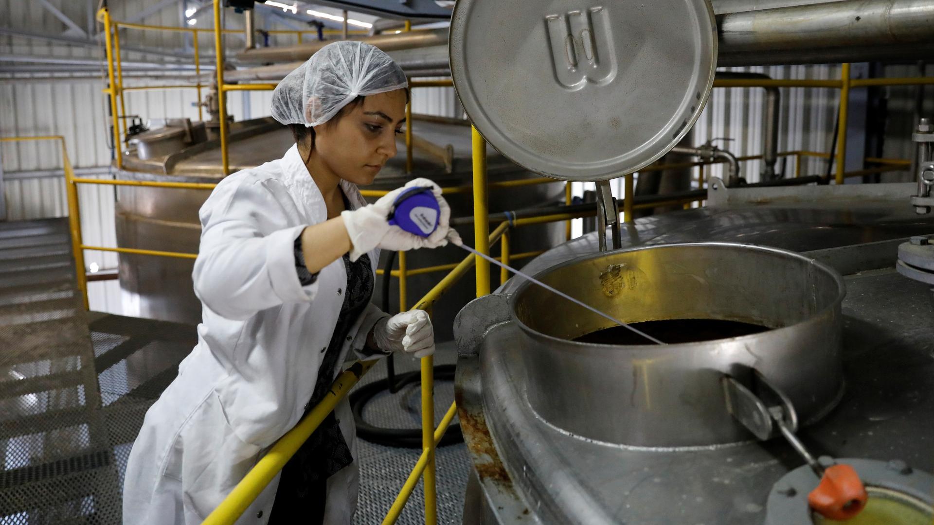 In this file photo, an employee takes a sample from a storage cylinder of Turkey's popular alcoholic drink rakı at the Infotex Alkollu Icecekler plant in the town of Dinar, Turkey, Nov. 30, 2017.