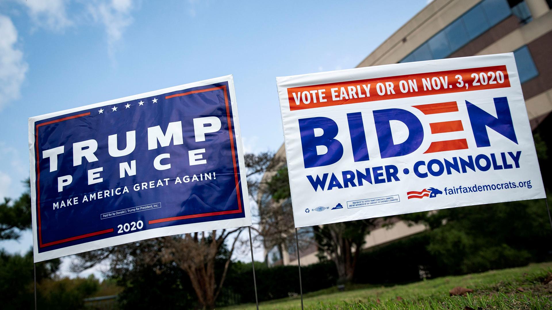 Two political yards signs are shown side-by-side — a mostly blue-colored Trump sign and a white with blue lettering Biden sign.
