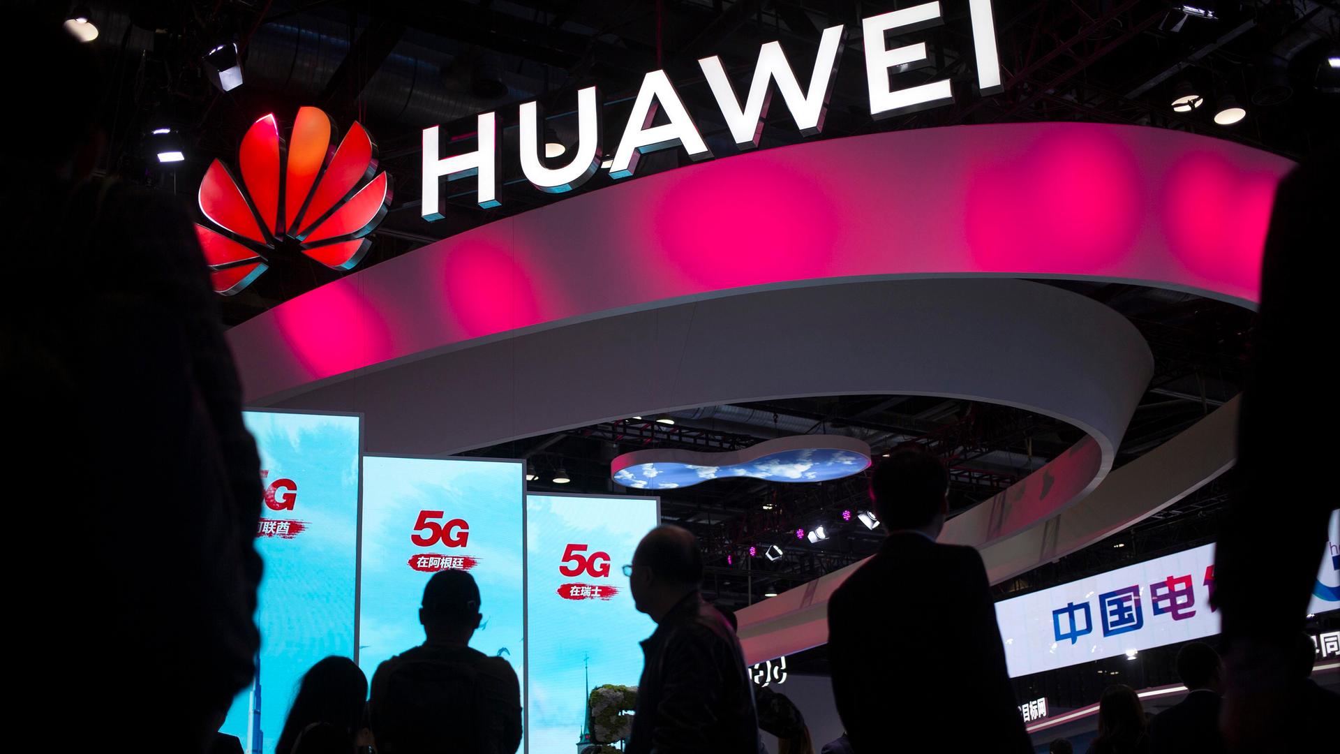 In this Oct. 31, 2019, file photo, attendees walk past a display for 5G services from Chinese technology firm Huawei at the PT Expo in Beijing.