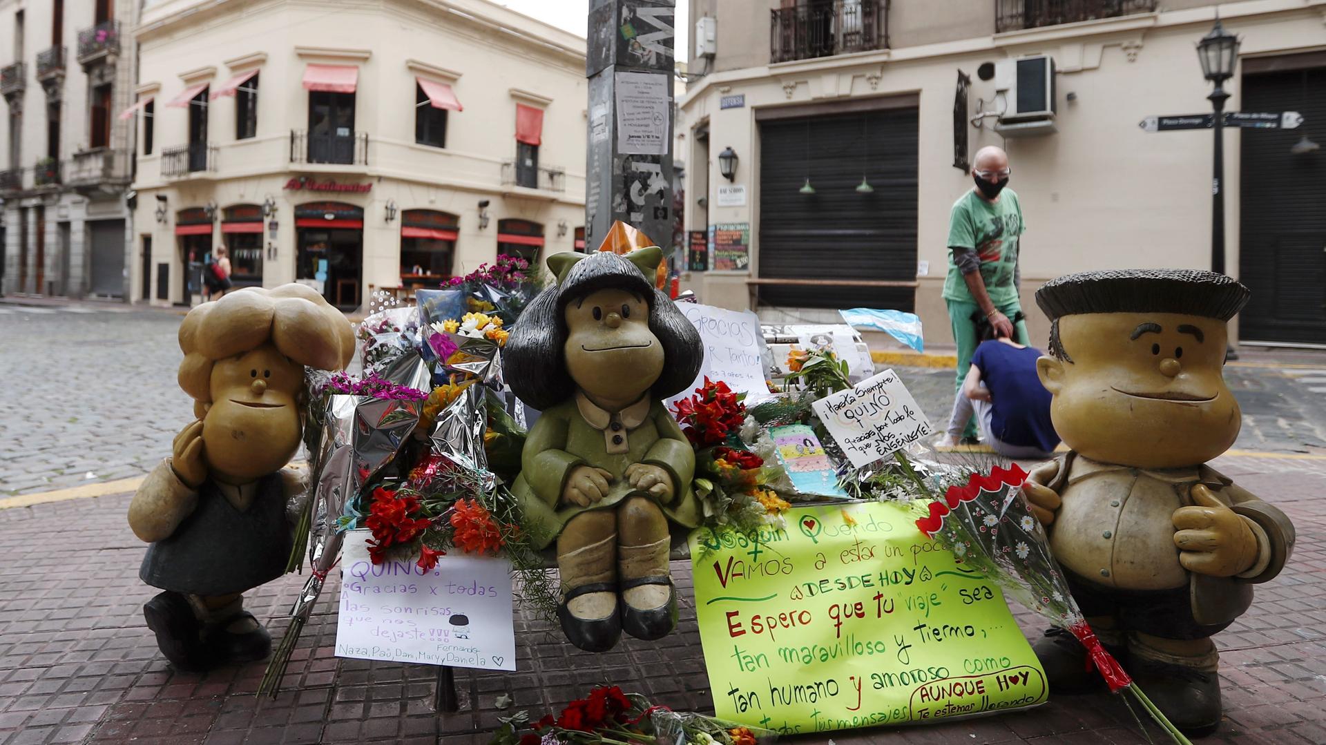 A woman mourns the death of cartoonist Joaquin Salvador Lavado, also known as Quino, who died yesterday at the age of 88, as flowers and tributes are seen next to sculptures of comic characters Mafalda, Susanita, and Manolito, created by him, in Buenos Ai