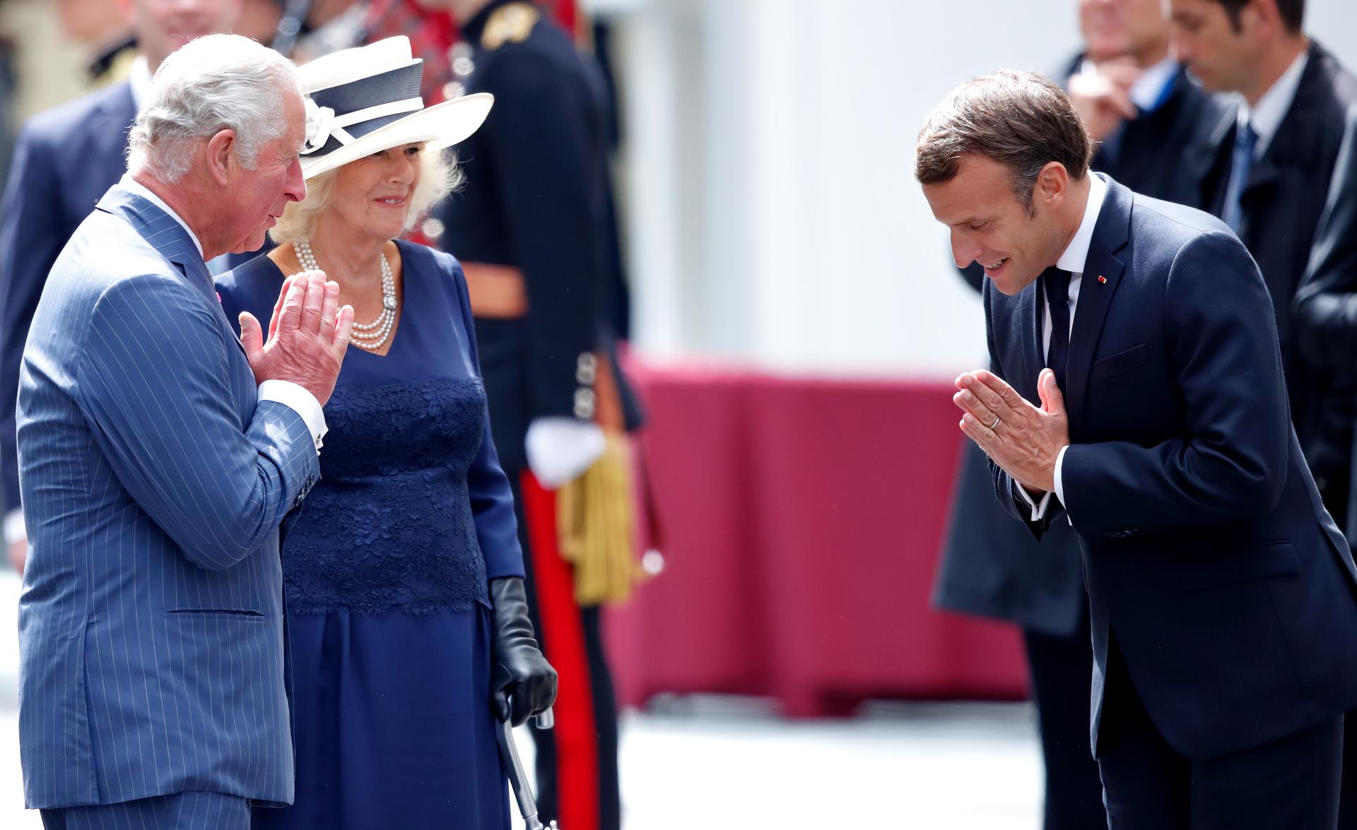 Prince Charles, the Duchess of Cornwall, and Emmanuel Macron greet each other with a 'namaste' on an airport tarmac