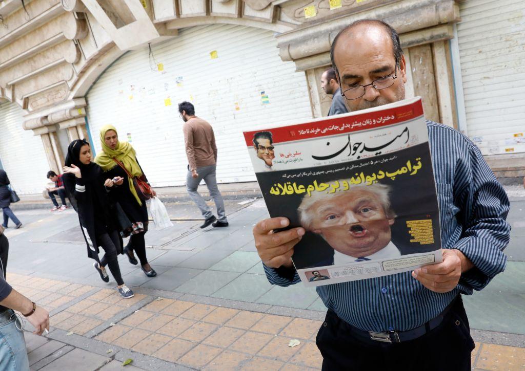A man reads an Iranian newspaper with a sensational photo of U.S. President Trump on the cover.