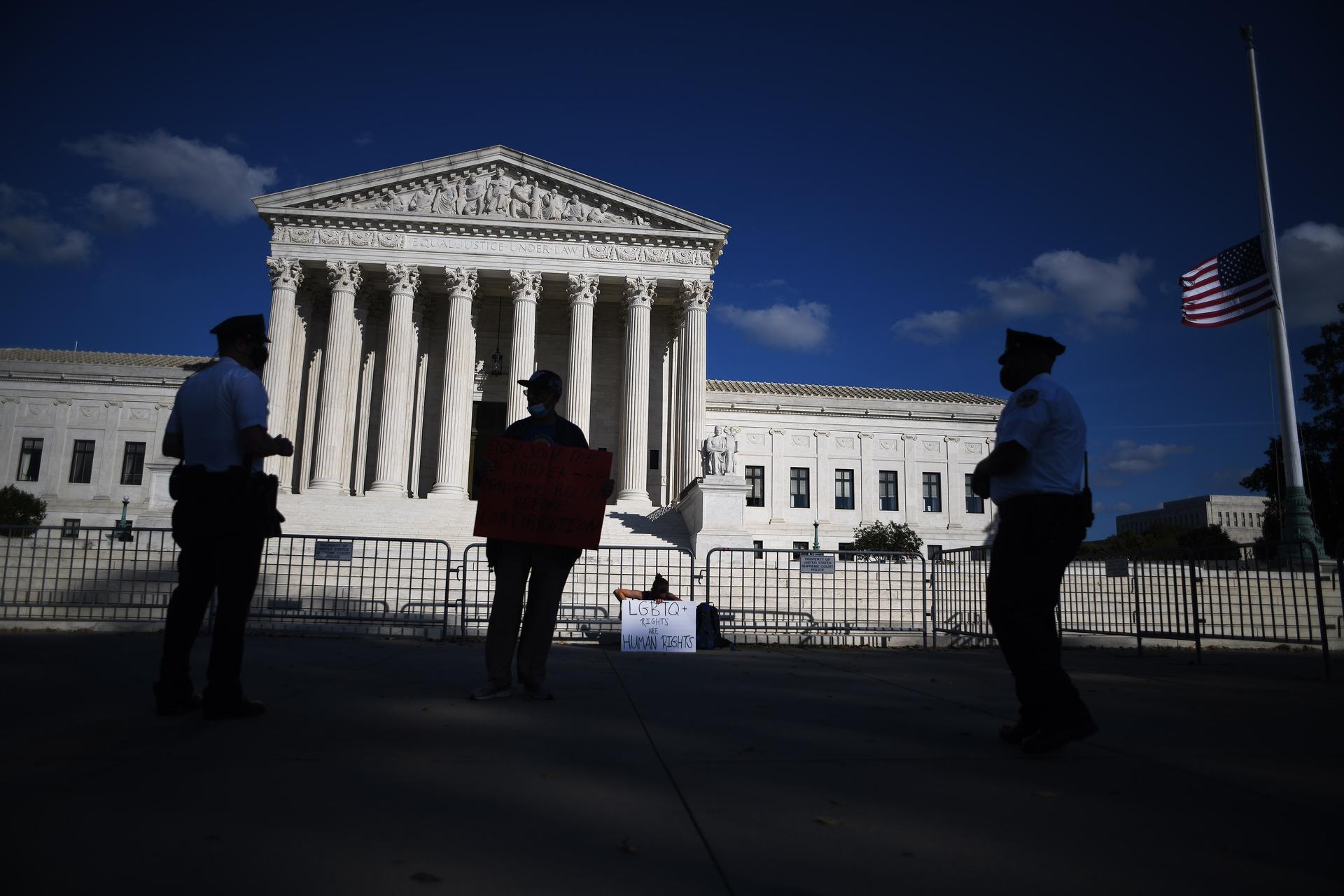 Police officers talk to one of two demonstrators who gather outside the Supreme Court in Washington, D.C., October 15, 2020, to protest the nomination of Justice Amy Coney Barrett.