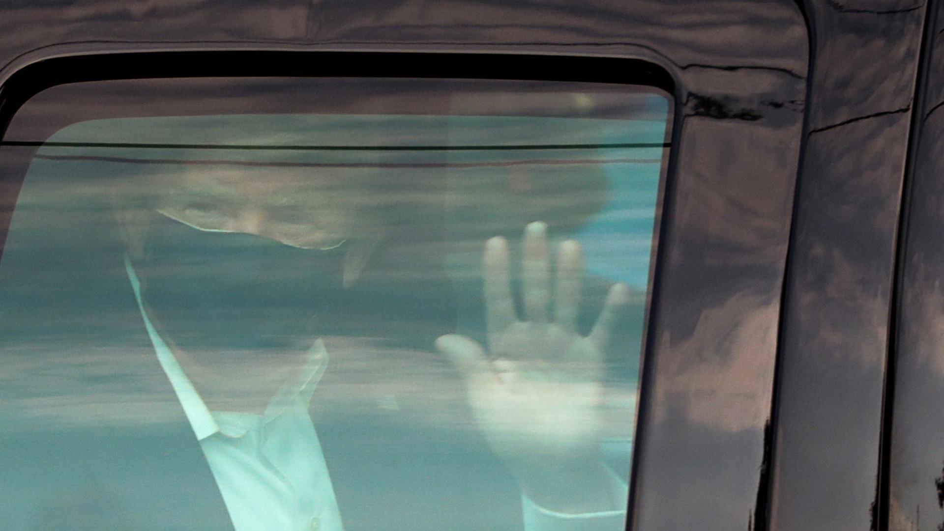 President Donald Trump waves to supporters as he briefly rides by in the presidential motorcade in front of Walter Reed National Military Medical Center, where he is being treated for the coronavirus in Bethesda, Maryland, Oct. 4, 2020.  