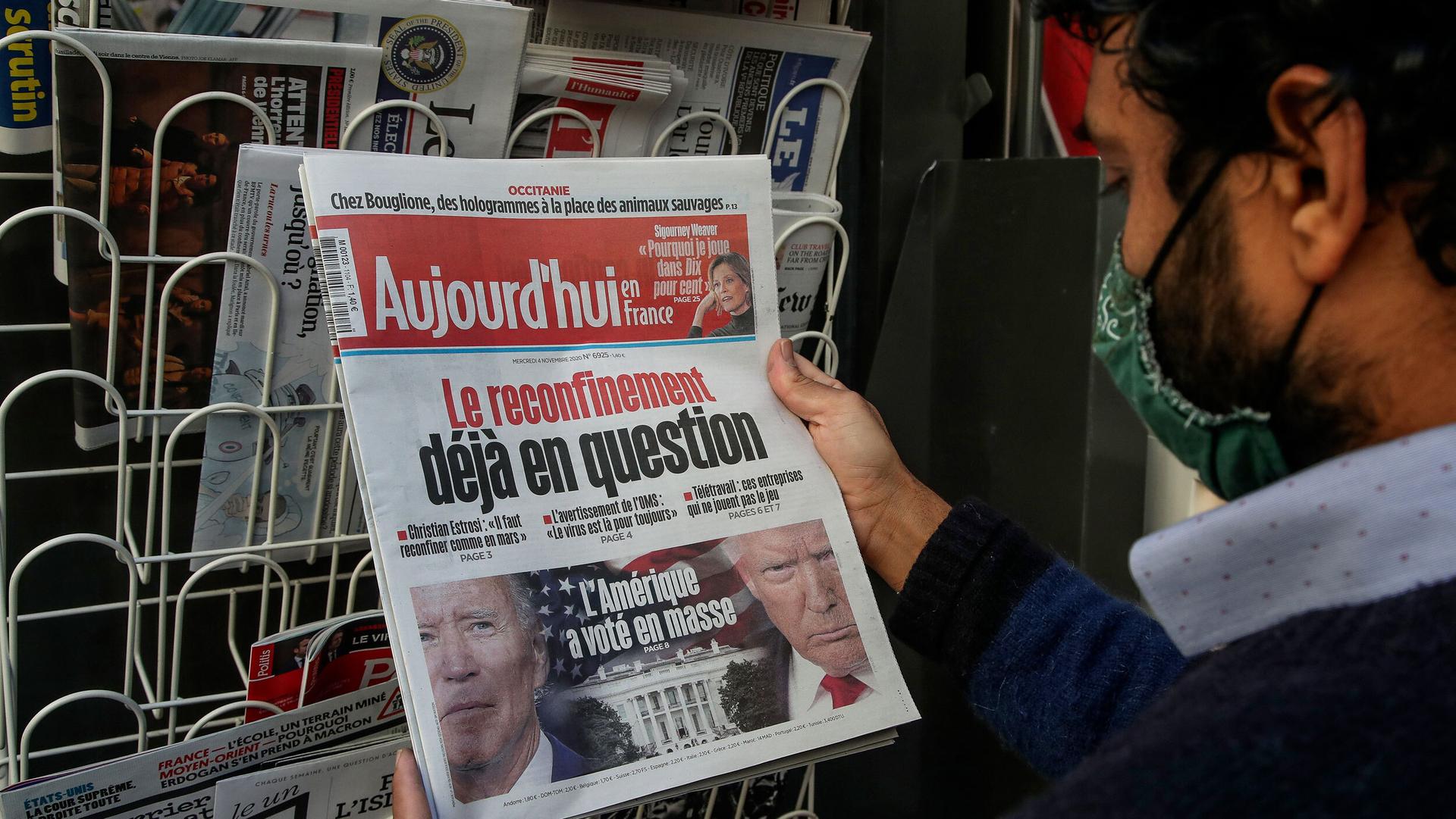 A man reads the headline about the US presidential election at a newspaper stand in Paris, France, Nov. 4, 2020.