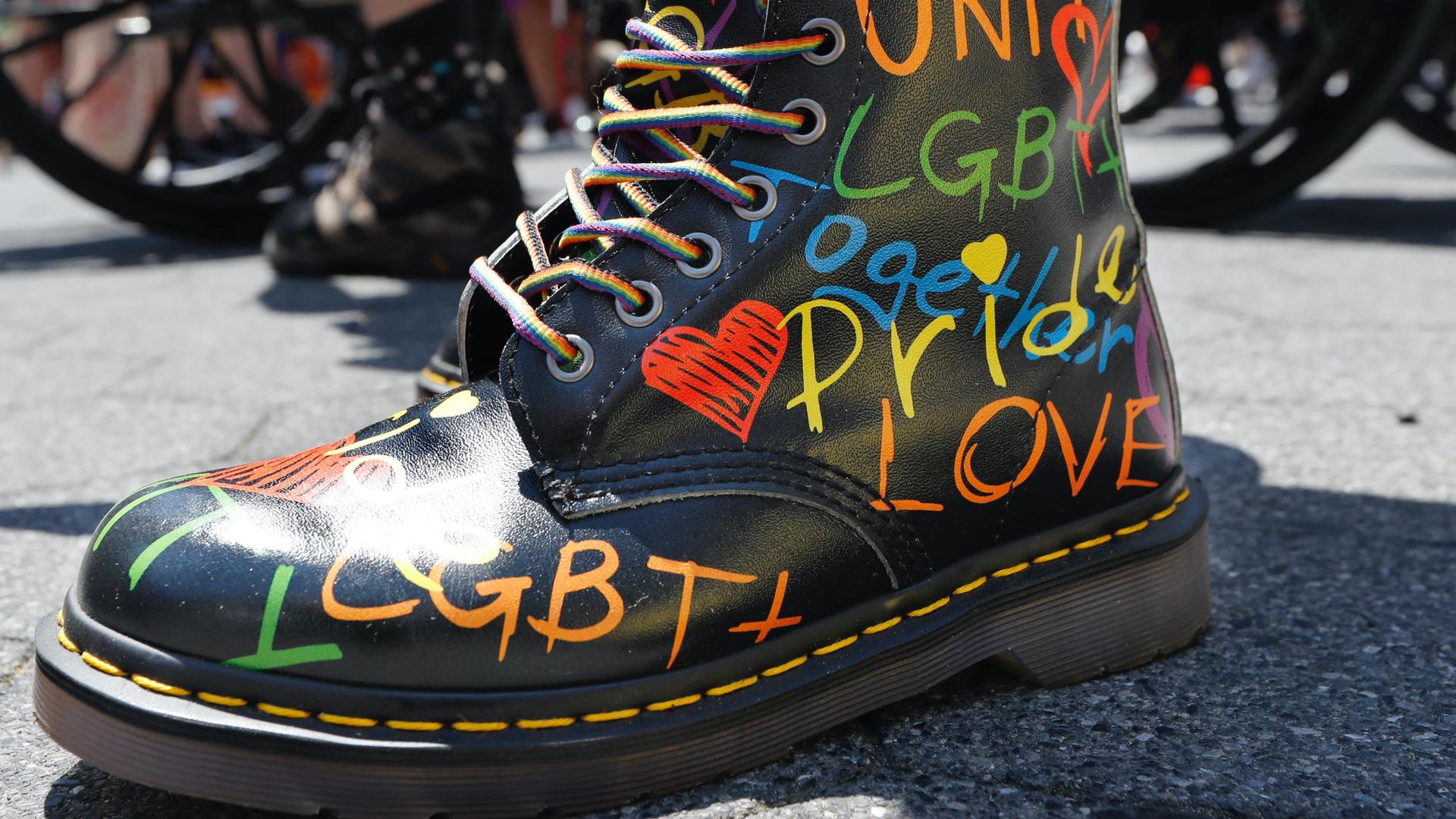 A person wears colorful, pride-themed boots as they await the start of a queer liberation march for Black Lives Matter and against police brutality