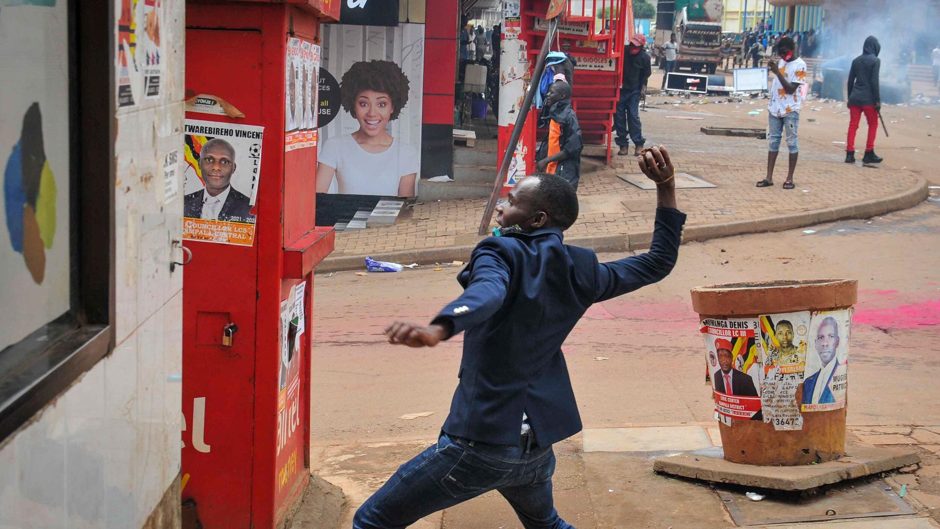 A person prepares to throw a rock during clashes between security forces and protesters supporting opposition presidential candidate Bobi Wine, in downtown Kampala, Uganda, Nov. 18, 2020.