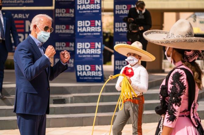Joe Biden interacts with two Latinos wearing sombreros and Biden/Harris masks.