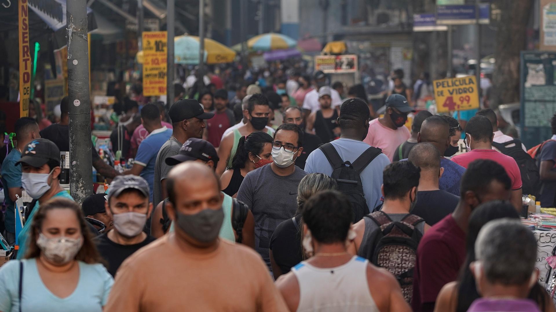 A crowded street is shown with some people wearing face masks.