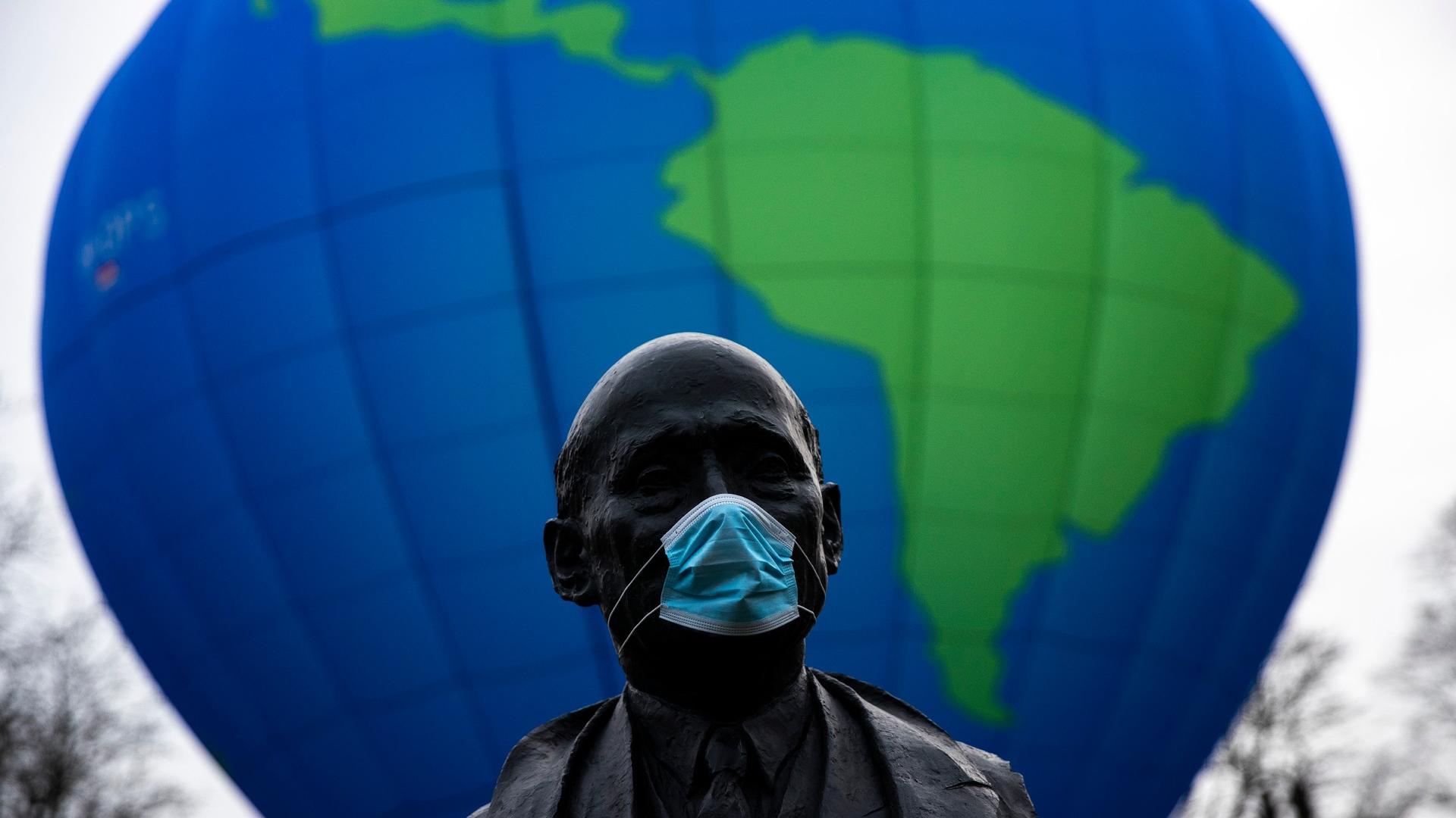 The bust of French statesman Robert Schuman, one of the founders of the European Union, is seen while environmental activists launch a hot air balloon during a demonstration outside of an EU summit in Brussels, Belgium, Dec. 10, 2020.